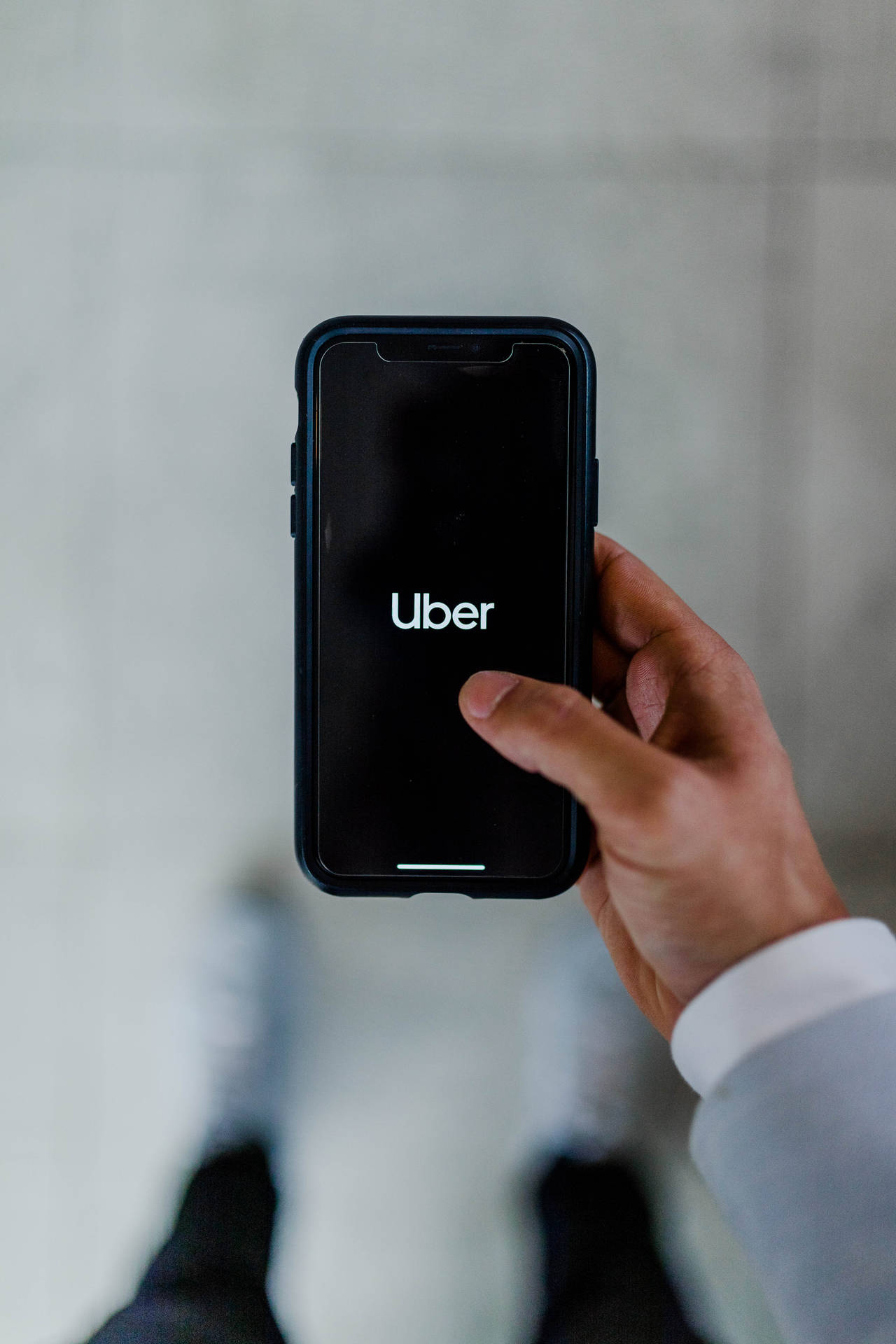 手拿著手機，螢幕上顯示Uber應用程式標誌 — 汽車 iPhone 壁紙 壁紙