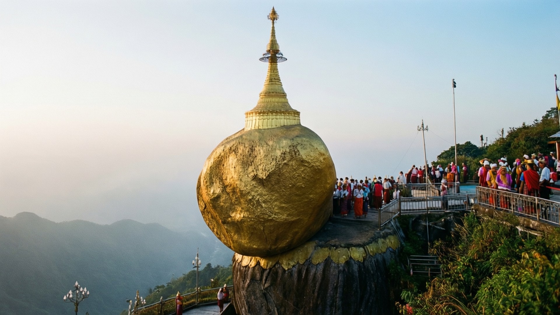 Golden Rock Pilgrimage 壁紙 — 一座巨大的金色寶塔坐落在岩石露頭上，遊客聚集在觀景台上，俯瞰黎明時分霧氣繚繞的山巒。
