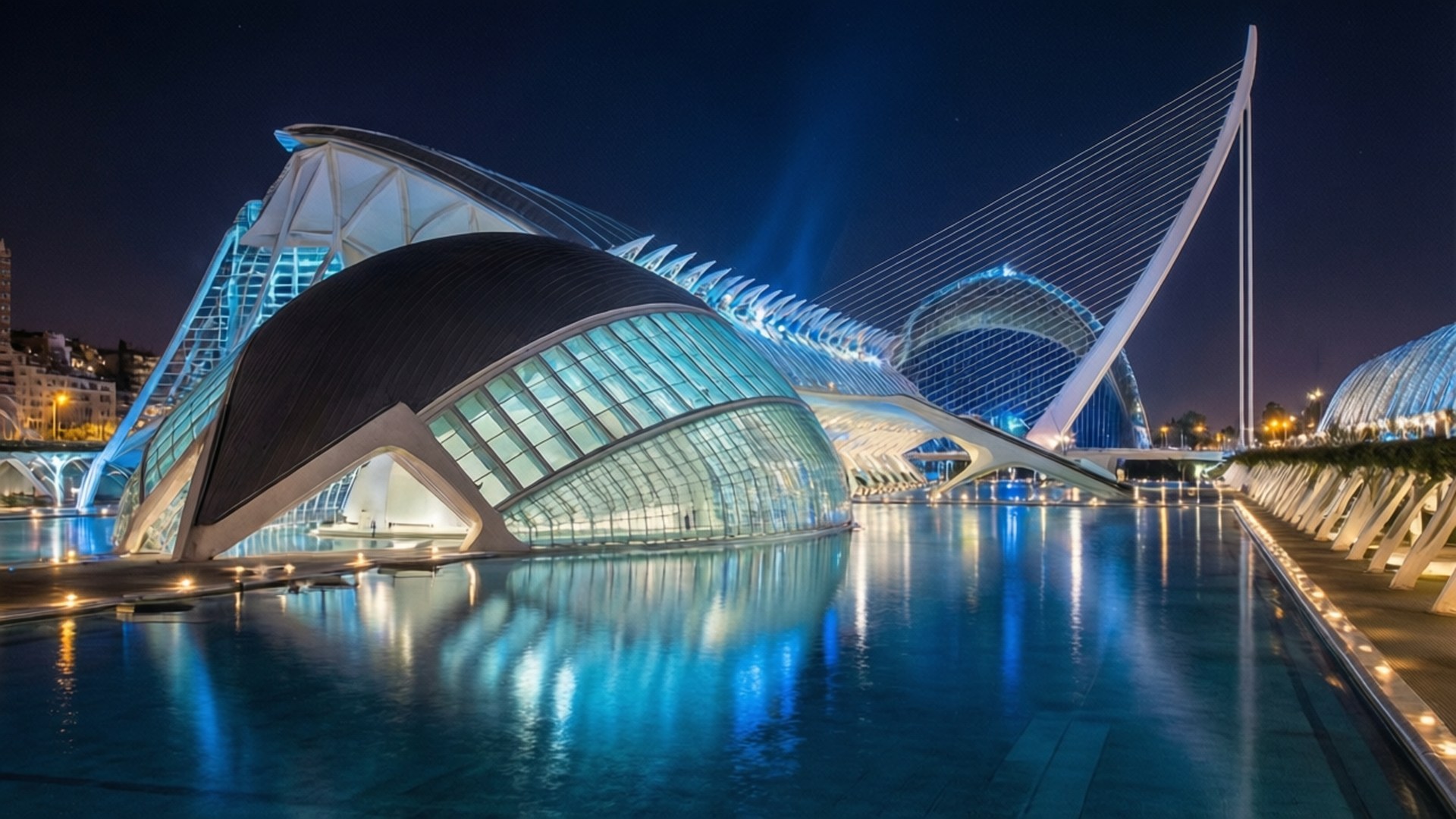 Valencia Arts and Sciences 壁紙 — 一座未來風格的玻璃和鋼鐵建築群在夜晚發出藍光，倒映在平靜的水面上。