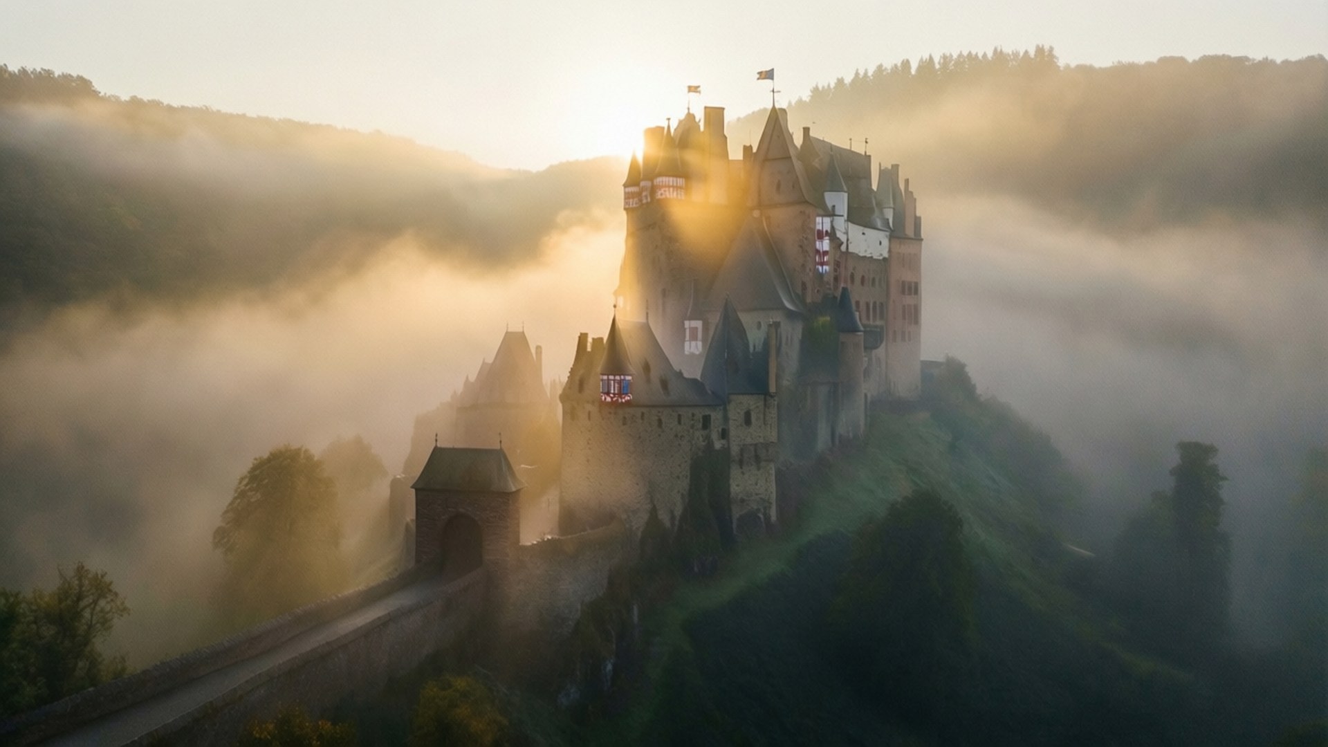 Foggy Dawn Castle 壁紙 — 一座雄偉的中世紀城堡坐落在霧氣瀰漫的山丘上，沐浴在金色的日出光芒中。