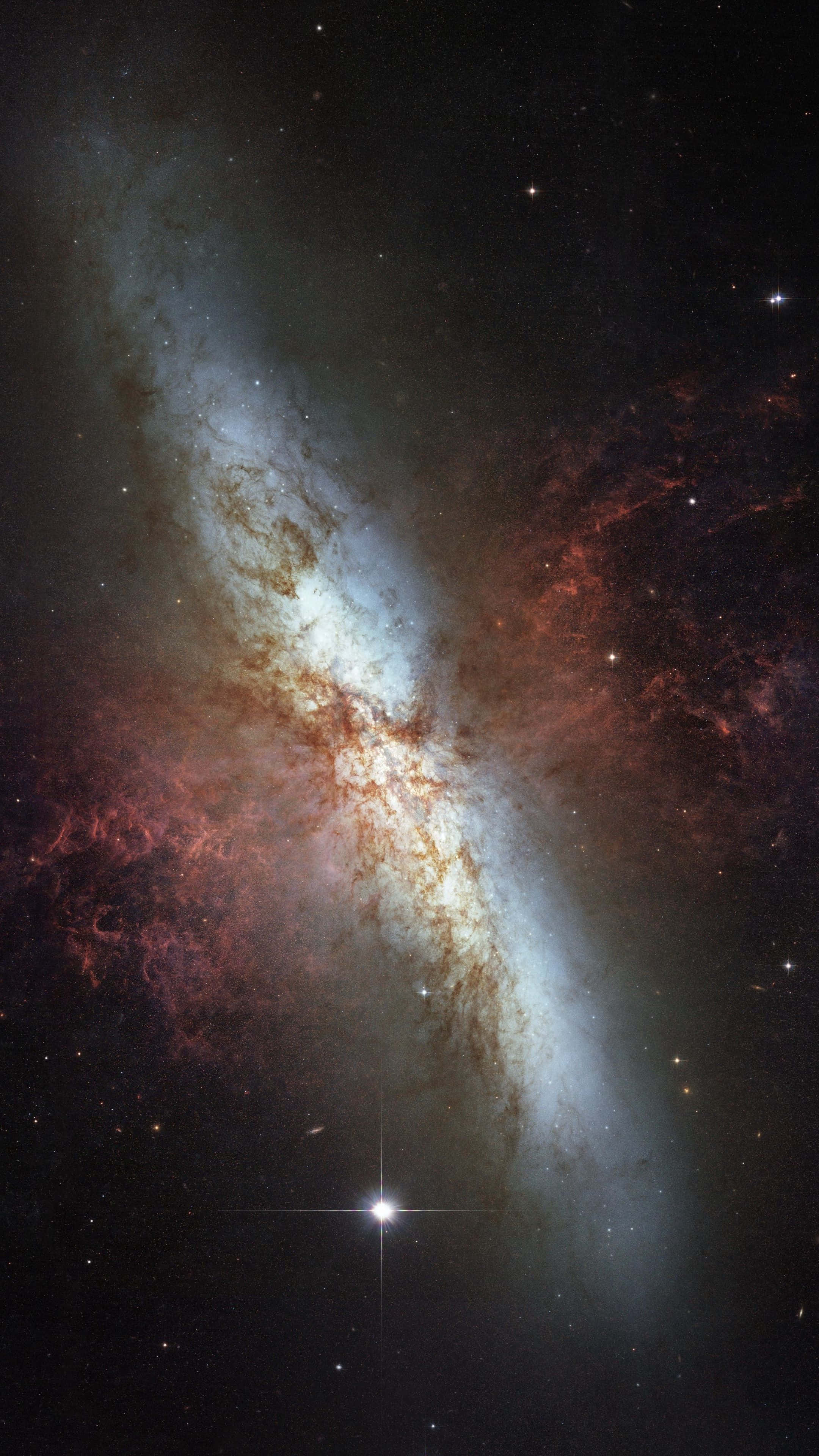 太空 桌布 壁紙 — 一個宏偉的螺旋星系在佈滿星辰的宇宙虛空中旋轉，散發著發光的藍色和火紅色的星雲。