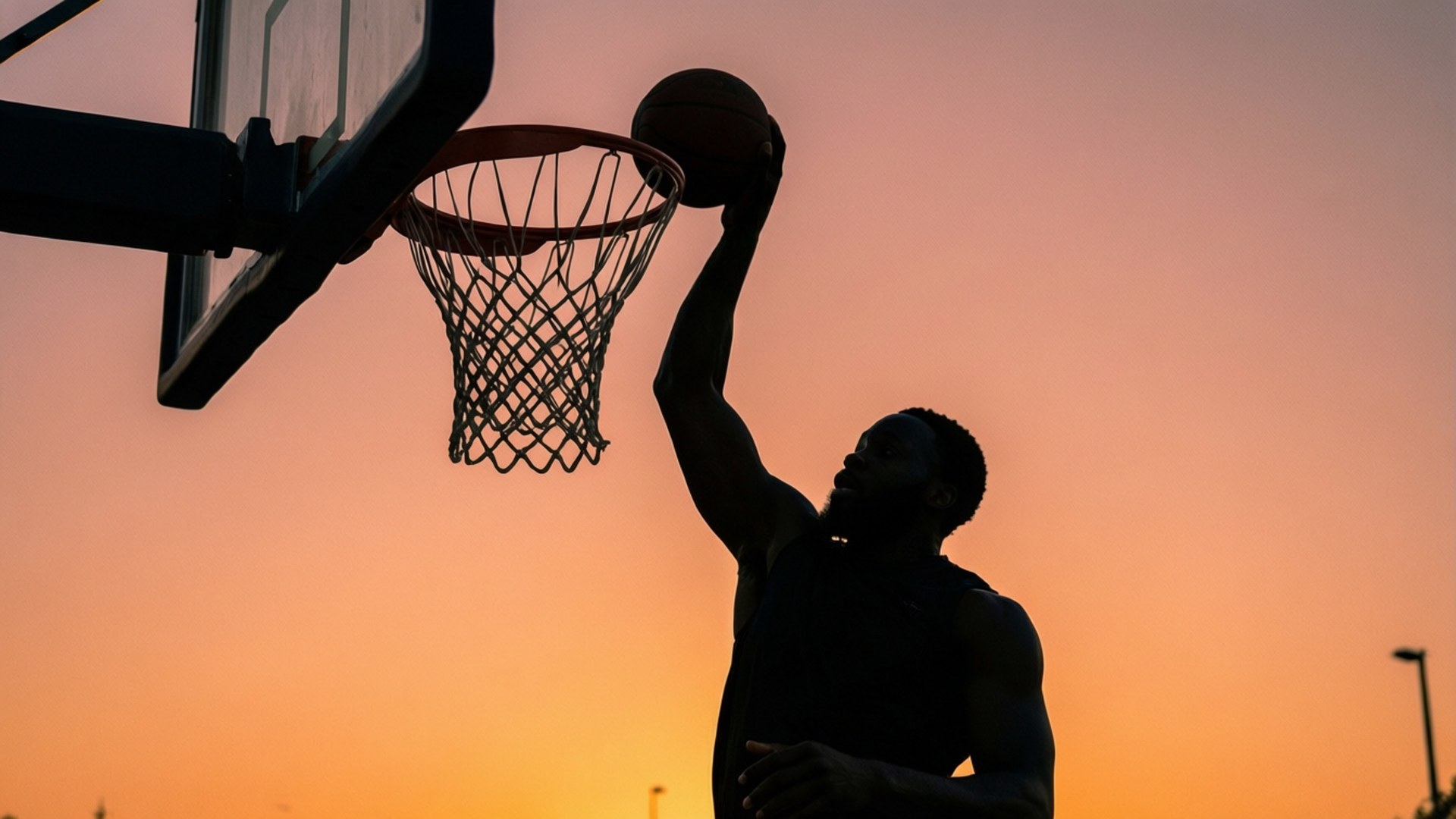 Sunset Slam 壁紙 — 一個籃球運動員在鮮豔的日落背景下呈現剪影，將球灌入籃框。