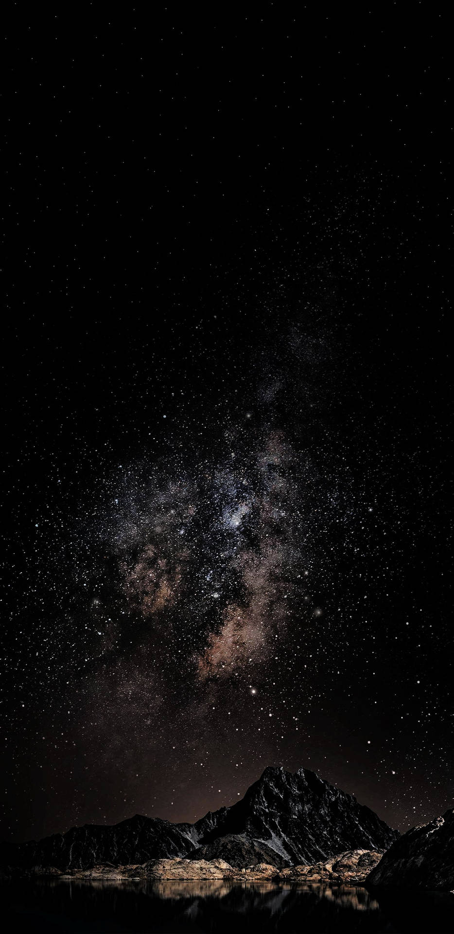 銀河星系在黑暗山脈之上，倒映在夜晚的平靜水面上。 — iPhone X 壁紙