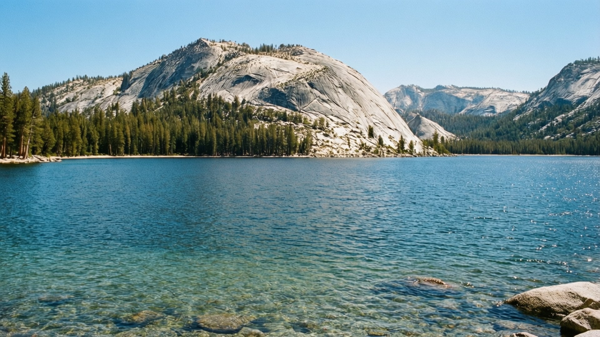 Tenaya Lake Serenity 壁紙 — 一個寧靜的湖泊，清澈見底的水面倒映著周圍的花崗岩山脈和茂密的松樹林，在明亮的藍天下。