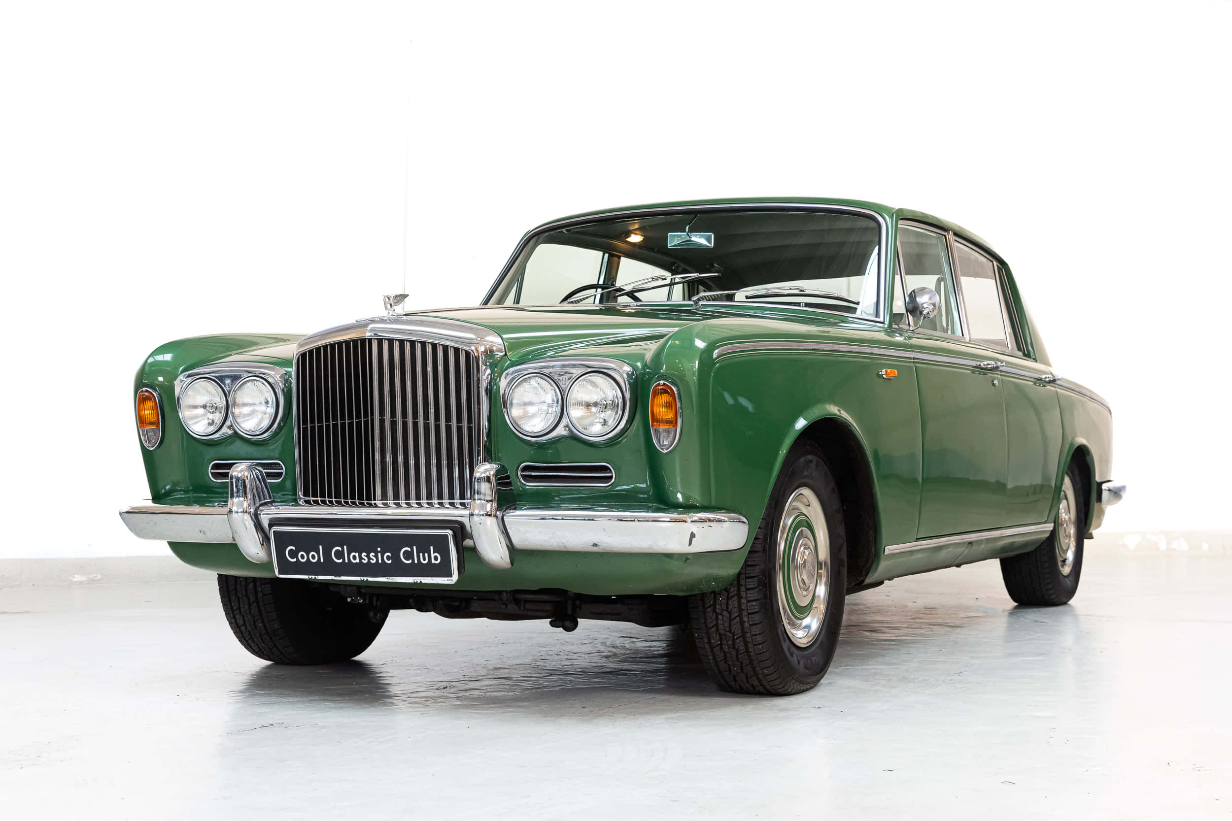Bentley T1 桌布 壁紙 — 一輛純淨的復古綠色賓利轎車在明亮的攝影棚燈光下，在潔白的背景上閃閃發光。