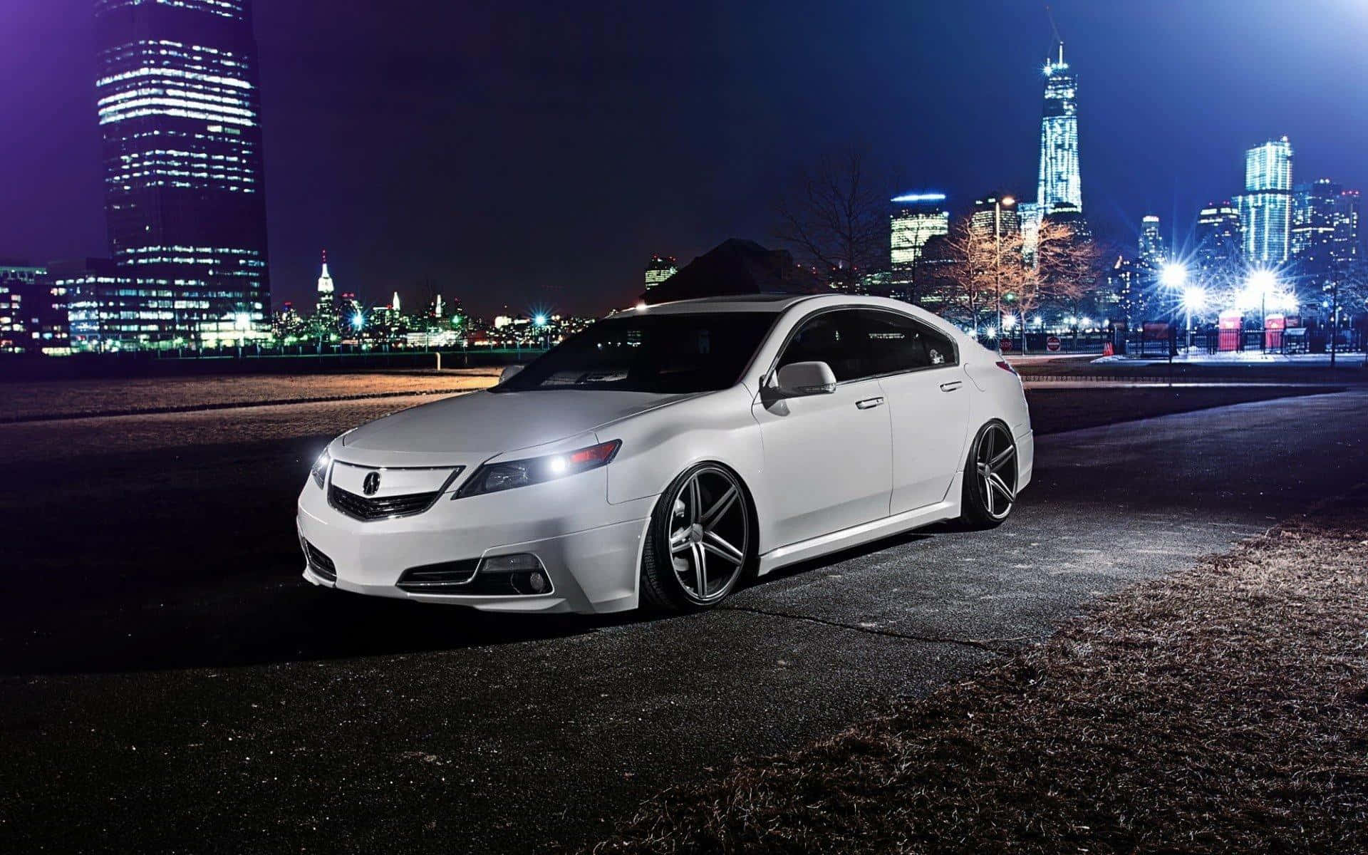 Acura Tl 桌布 壁紙 — 一輛時尚的白色轎車在城市的燈光下閃耀，映襯著充滿活力的夜景和燈火通明的摩天大樓。