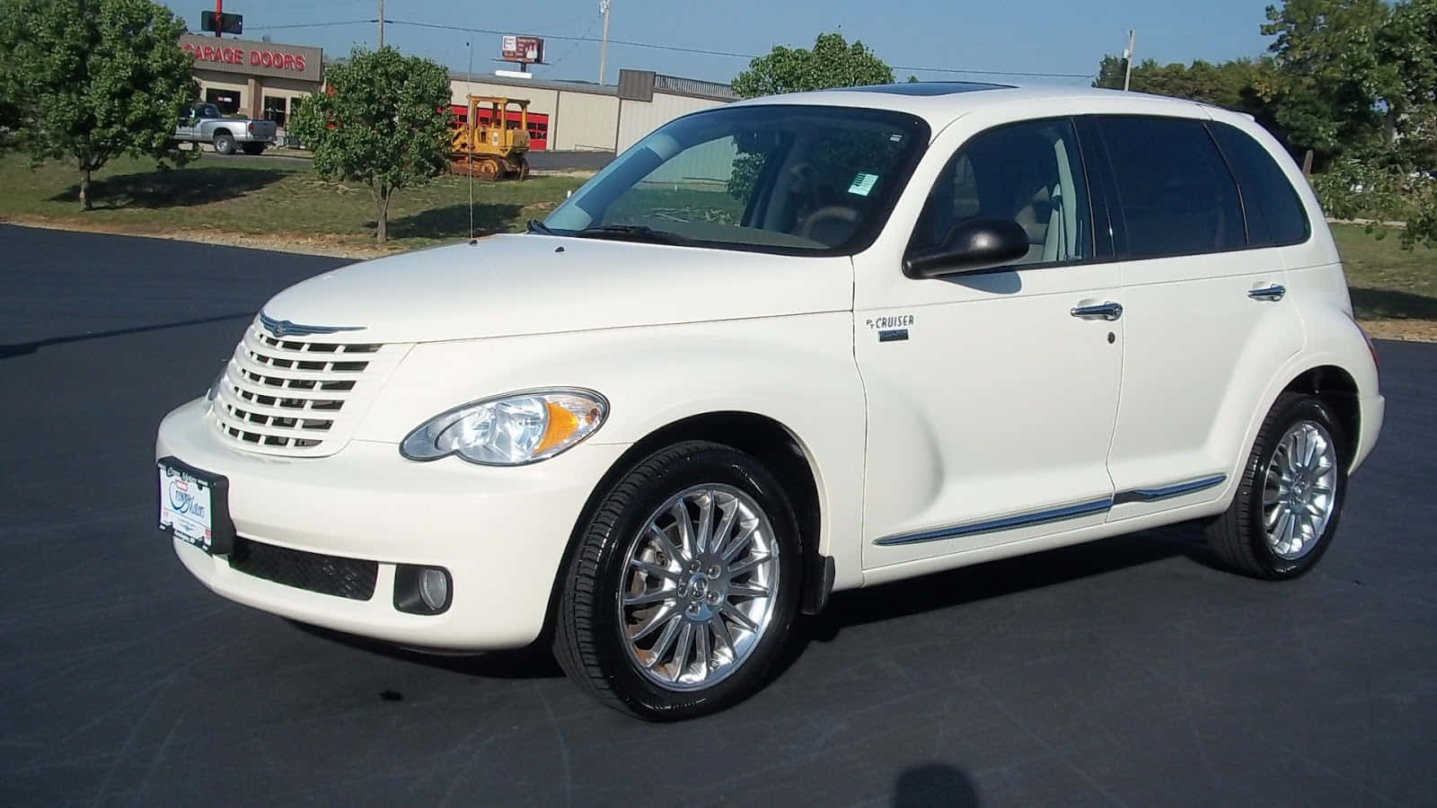 Chrysler Pt Cruiser 桌布 壁紙 — 一輛純白色的克萊斯勒 PT Cruiser 停在柏油路上，背景有樹木和一間車庫門公司。