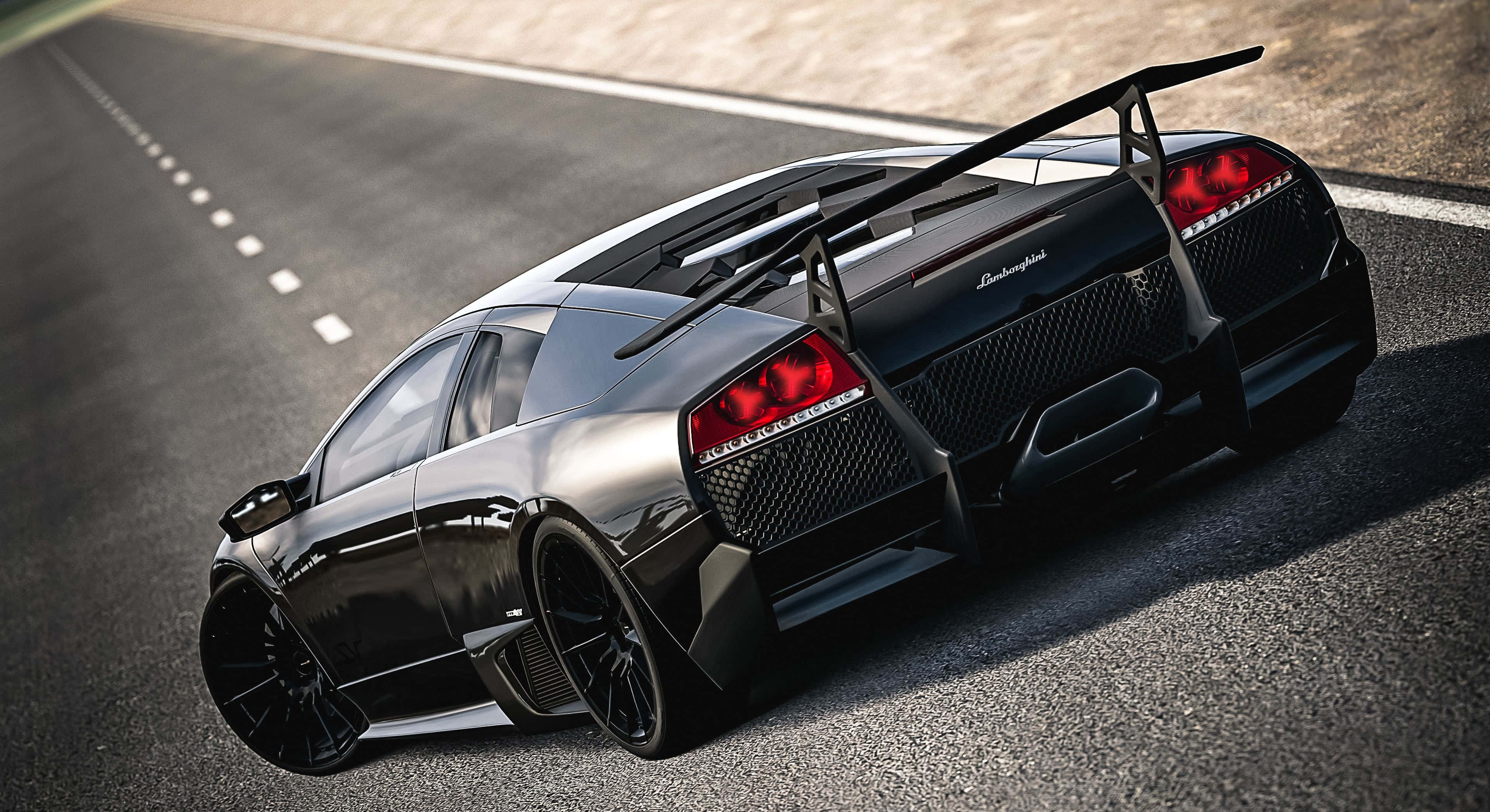 Lamborghini Murciélago 桌布 壁紙 — 一輛時尚的黑色藍寶堅尼跑車，帶有發光的紅色尾燈，在陽光明媚的瀝青路上飛馳。