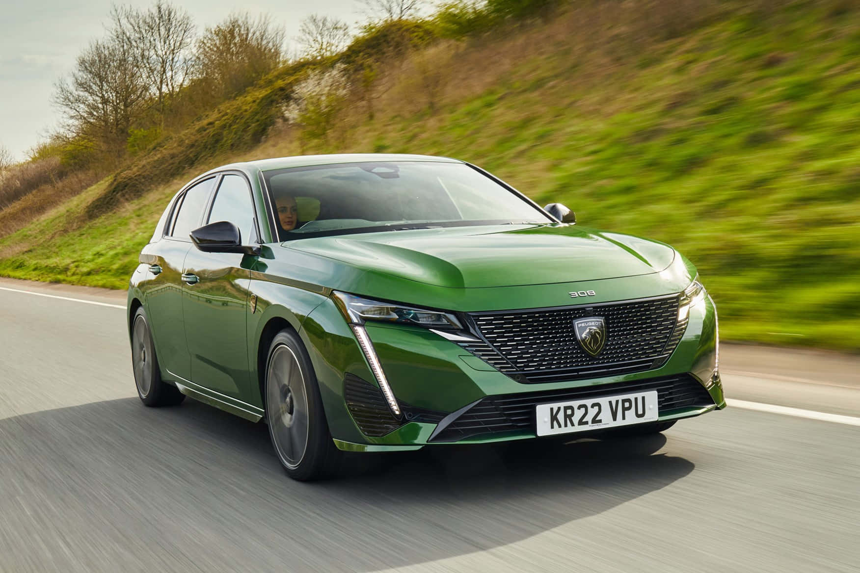 Peugeot 308 桌布 壁紙 — 一輛時尚的綠色Peugeot 308在蜿蜒的道路上疾馳，模糊的草地山坡飛掠而過。