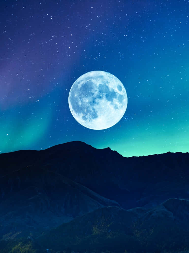  壁紙 — 一輪明亮的滿月懸掛在黑暗的山巒輪廓之上，下方是繁星點點的天空和充滿活力的綠色極光。