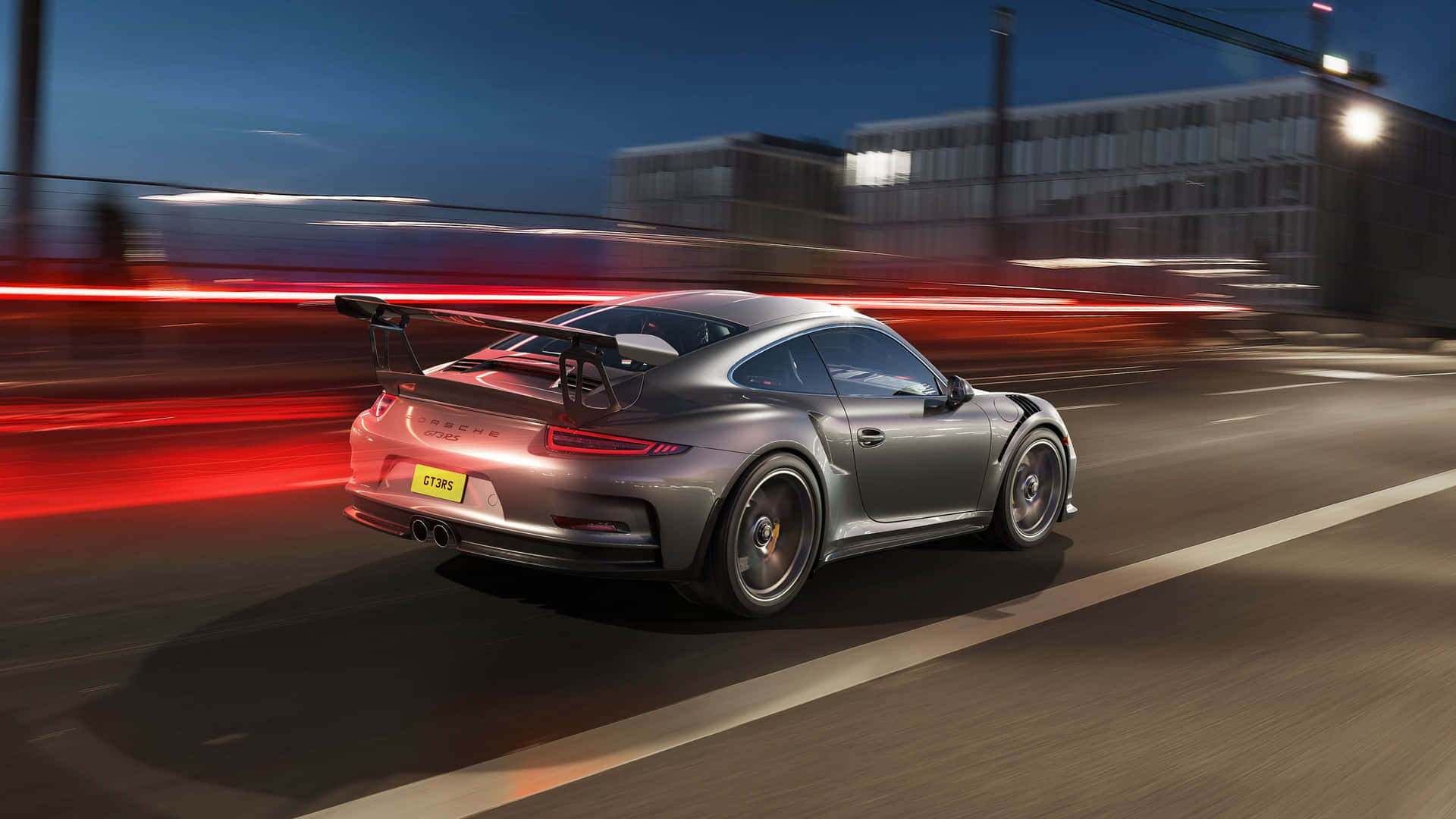  壁紙 — 一輛銀色保時捷 911 GT2 RS 在夜間高速穿梭城市，留下紅色尾燈和模糊的城市背景。