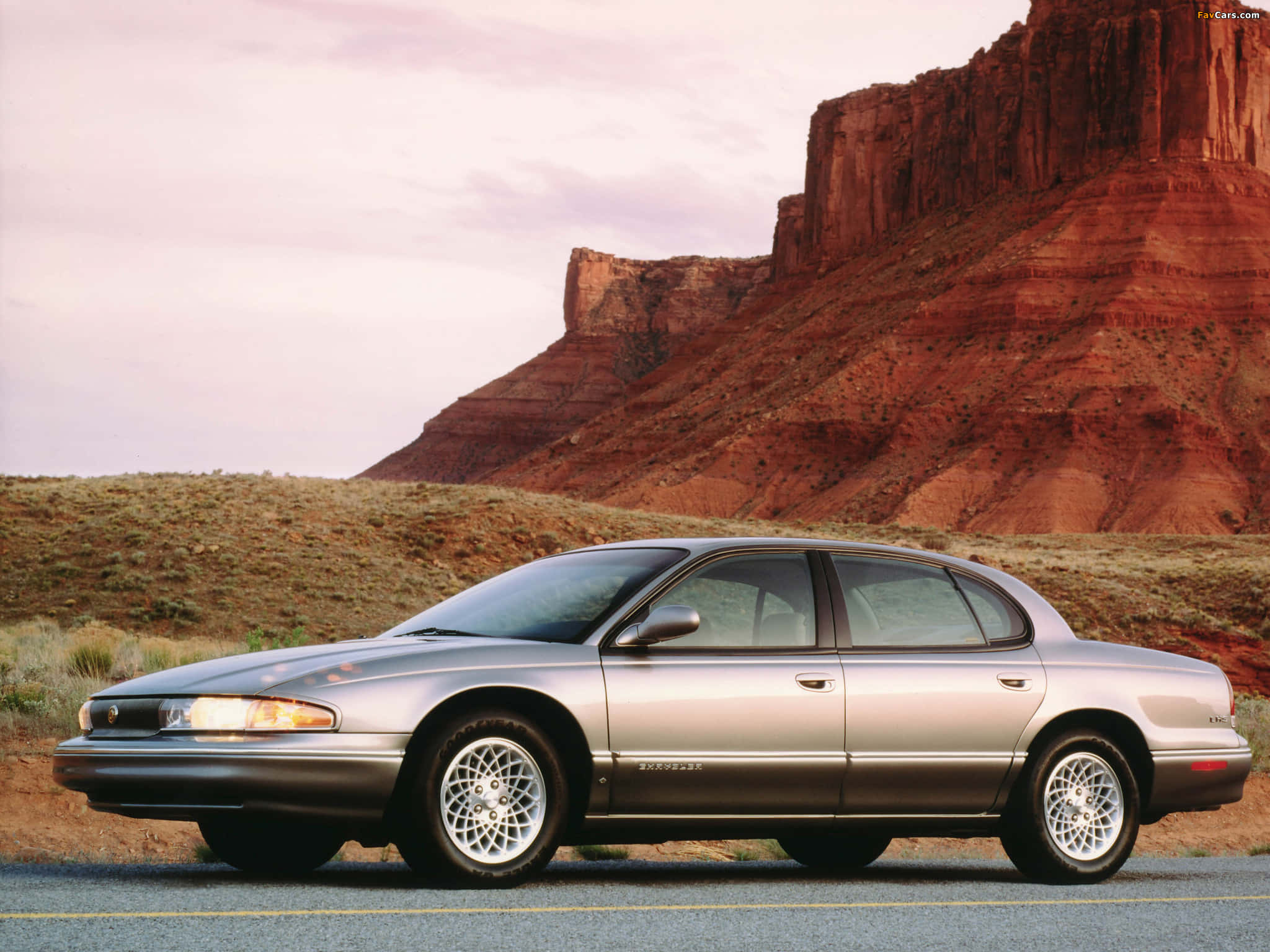 Chrysler Lhs 桌布 壁紙 — 一輛銀色別克Roadmaster轎車停在沙漠公路上，背後有紅色岩層在柔和暮色下升起。