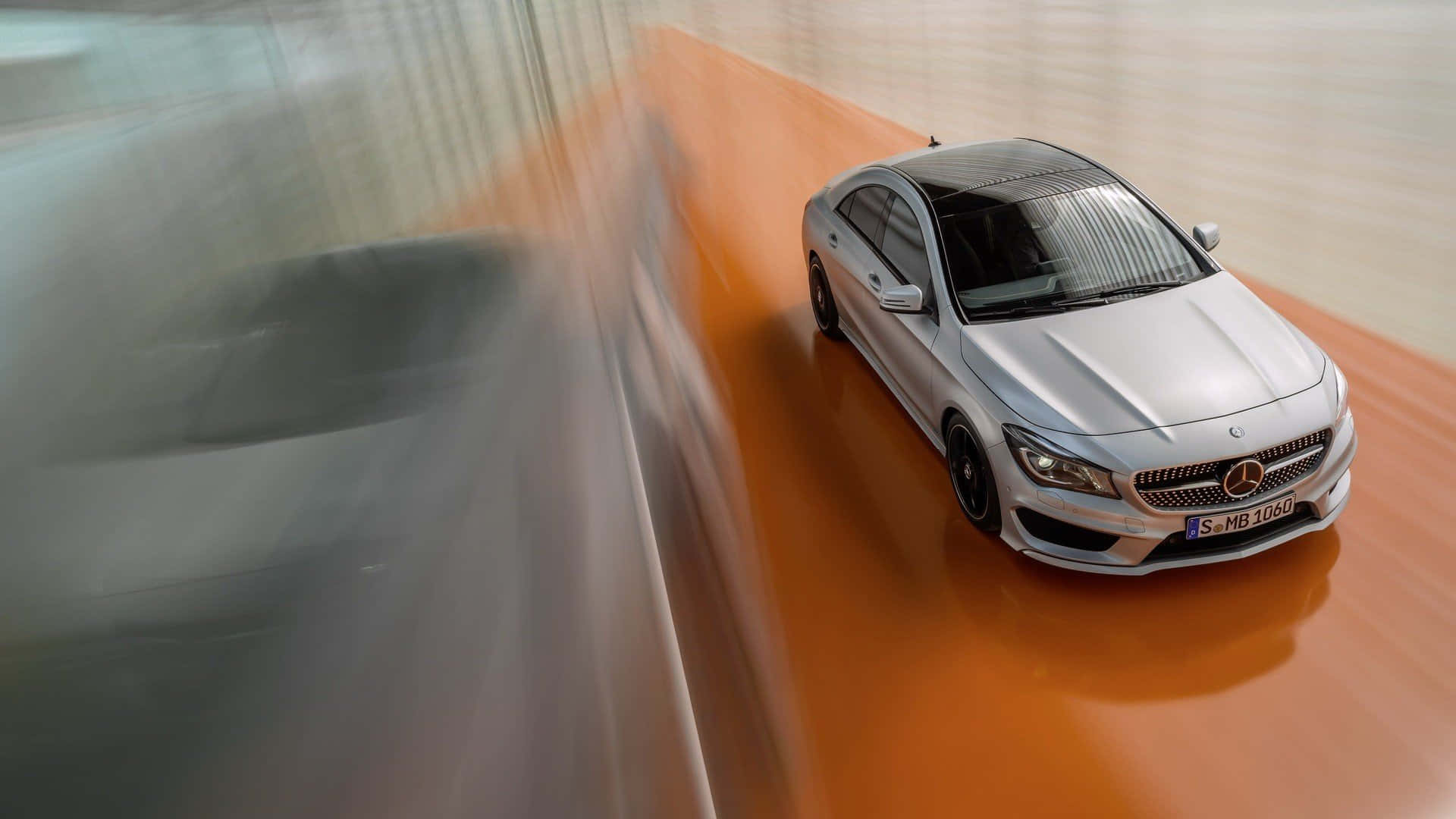 Mercedes Benz Cla-class 桌布 壁紙 — 一輛銀色賓士CLA轎車在橙色賽道上高速行駛，動態模糊傳達高速與時尚設計。