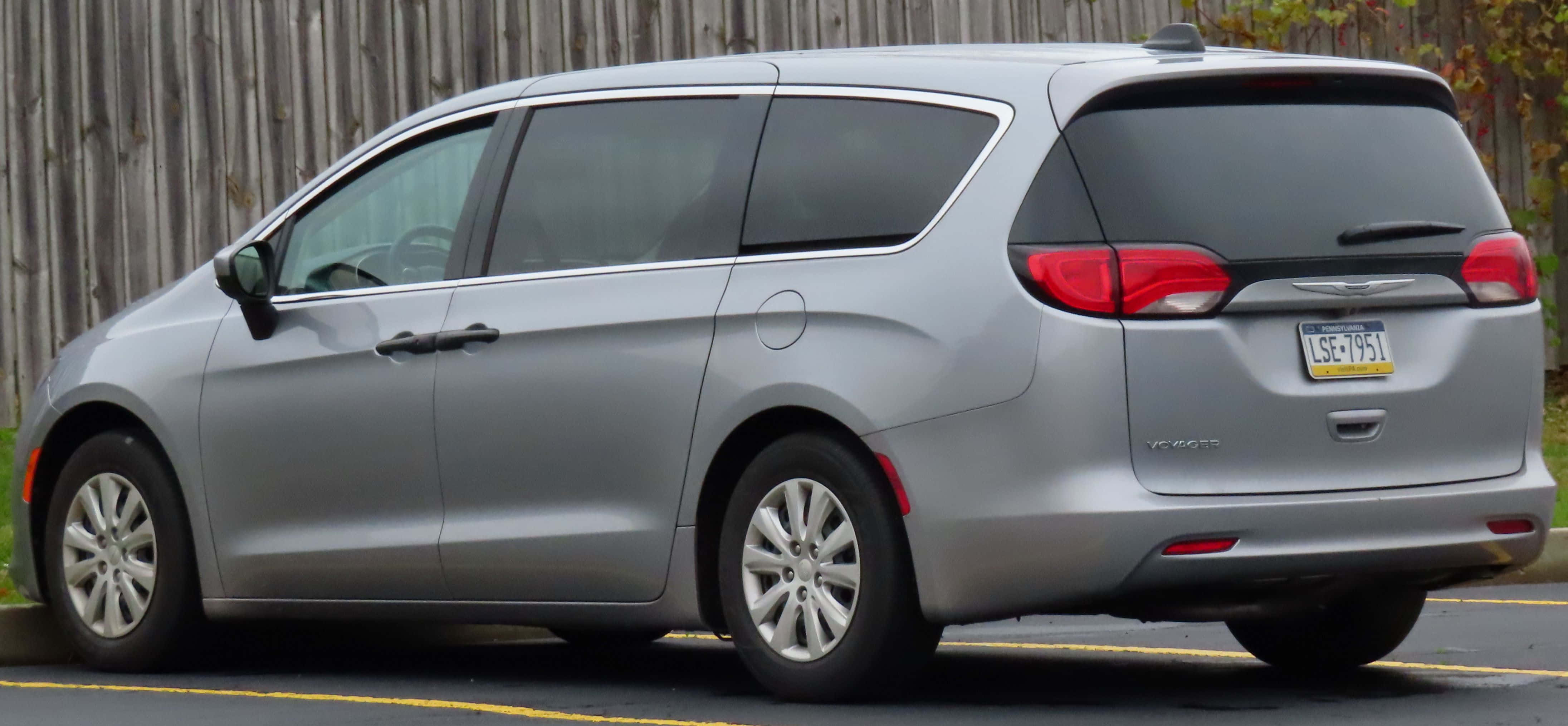 Chrysler Voyager 桌布 壁紙 — 一輛銀色 Chrysler Pacifica 小型貨車傾斜停放在經風化的木柵欄旁，附近有秋葉。