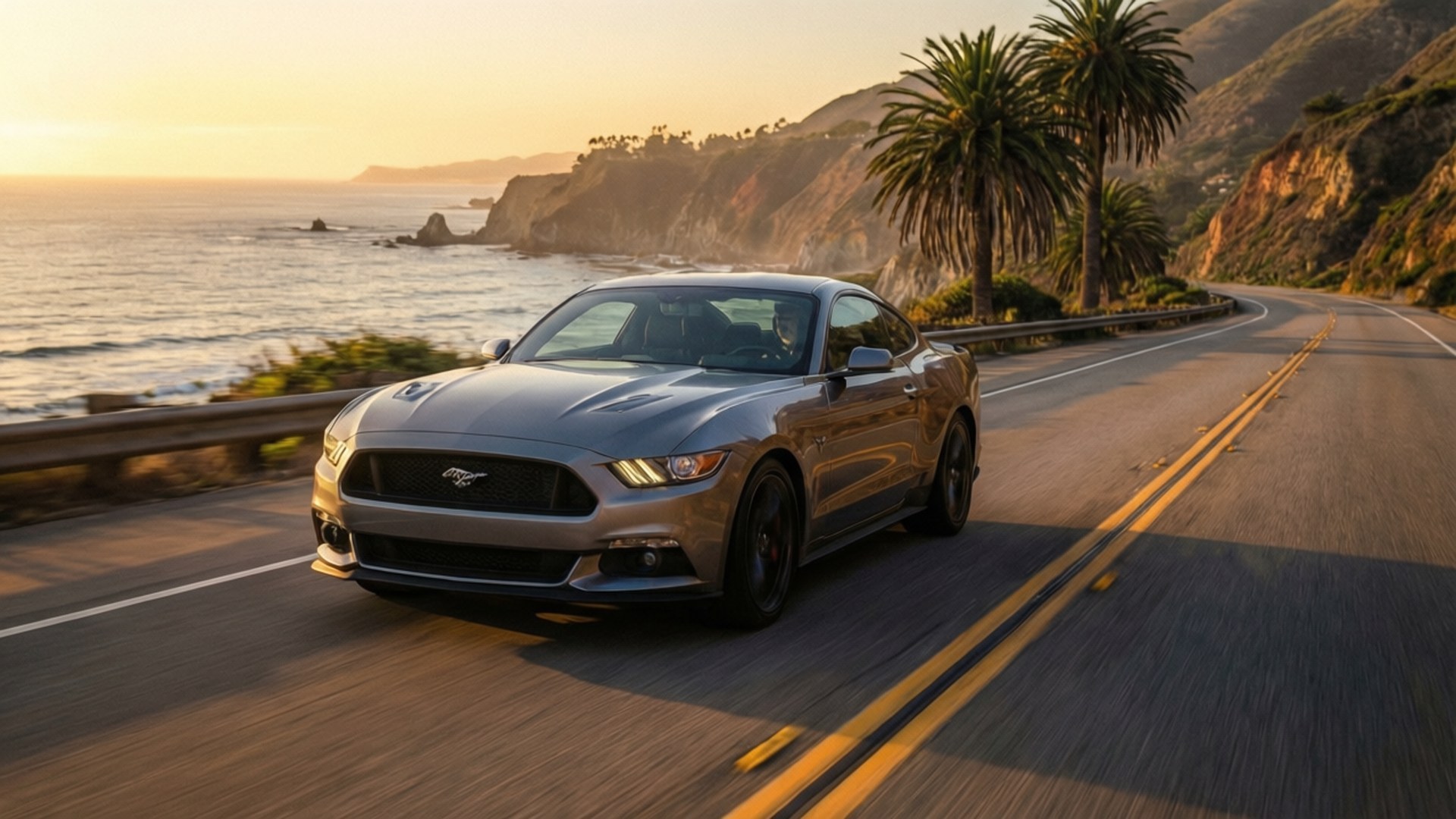 Coastal Sunset Mustang 壁紙 — 一輛銀色福特野馬在日落時分沿著海岸公路行駛，背景有棕櫚樹和海洋懸崖。