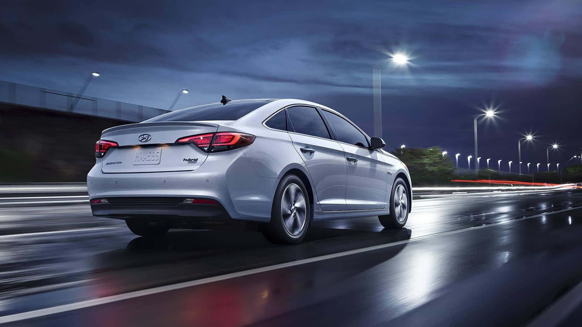 Hyundai Sonata 桌布 壁紙 — 一輛銀色現代轎車在夜間濕滑的高速公路上奔馳，街燈的光影在路面上拖曳反射。