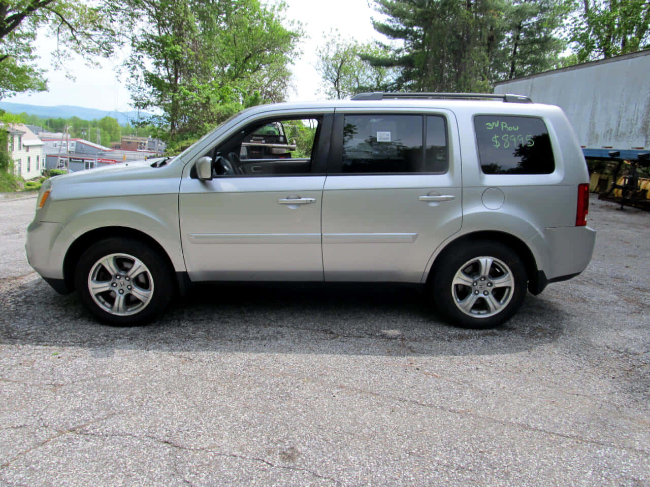 Honda Pilot 桌布 壁紙 — 銀色SUV停放在裂開的柏油路上，背景有樹木和遠山，在明亮日光下。