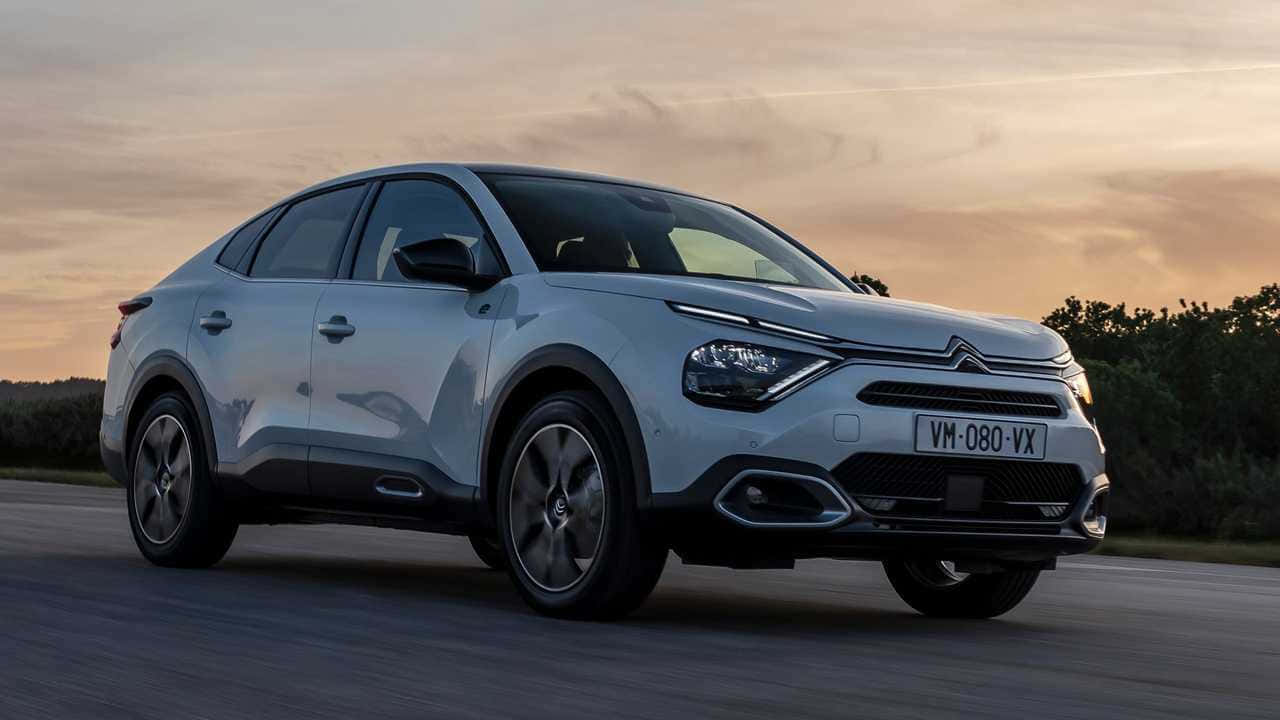  壁紙 — 一輛時尚的銀色雪鐵龍 C5 Aircross SUV 在日落時分沿著道路行駛，溫暖的金色光芒投下長長的影子。