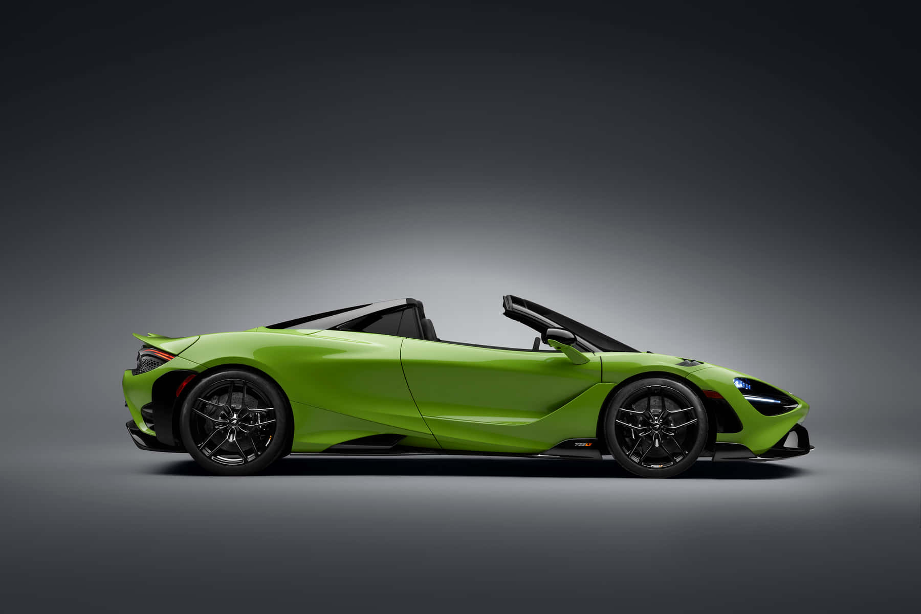 Mclaren 765lt 桌布 壁紙 — 一輛充滿活力的青檸綠色McLaren 720S Spider敞篷跑車，帶有黑色飾件和敞開車頂，在深灰色漸變背景的攝影棚中展示。