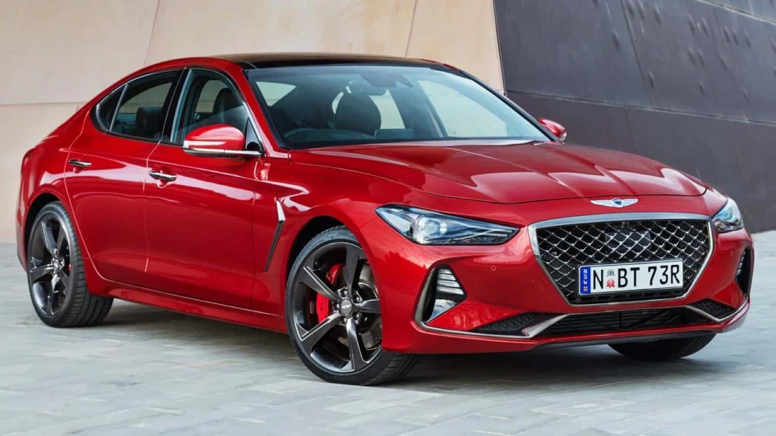 Genesis G70 桌布 壁紙 — 一輛亮紅色的Genesis G70運動轎車停放在現代混凝土牆旁，配備黑色合金輪圈。