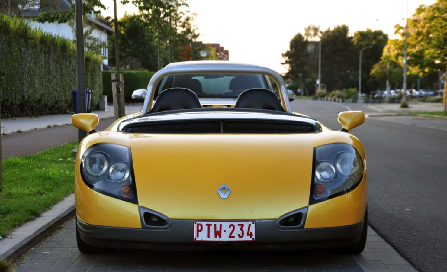 Renault Sport Spider 桌布 壁紙 — 一輛亮黃色的雷諾Twizy電動車在黃金時刻停放在寧靜的住宅街道上。