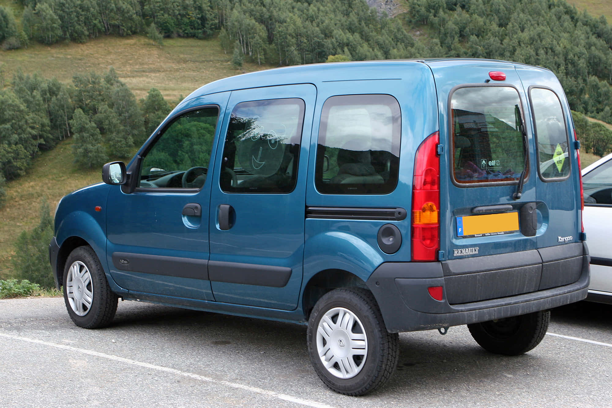 Renault Kangoo 桌布 壁紙 — 一輛藍色雷諾Kangoo客貨車停放在停車場，背景是綠色的森林山丘。