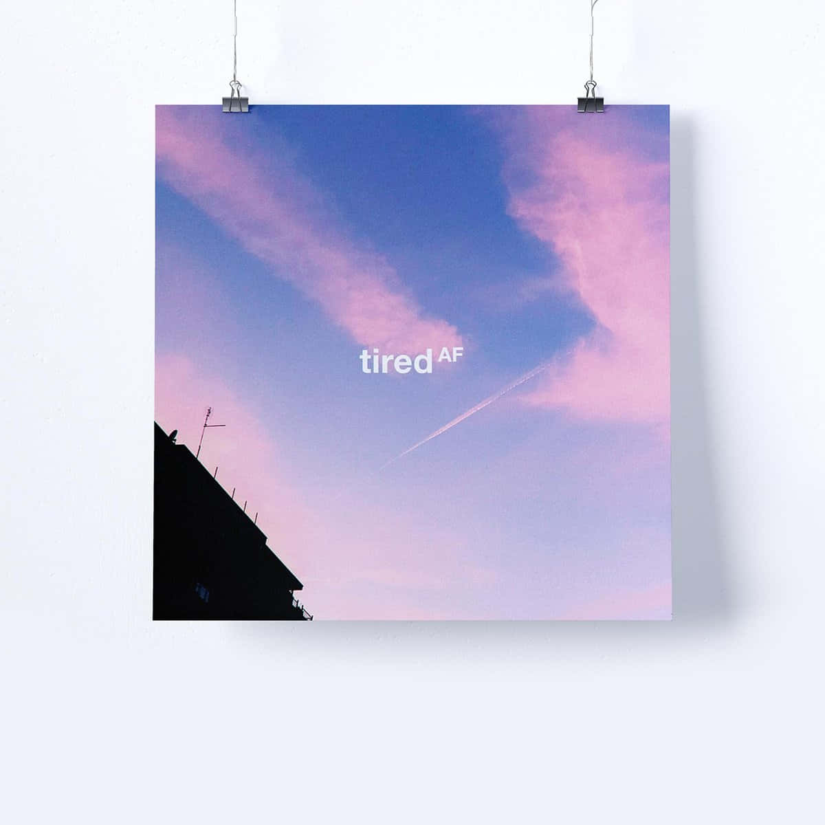  壁紙 — 一張寫有「tired AF」字樣的海報掛在白色牆上，背景是粉紅色和藍色的天空及建築物剪影。