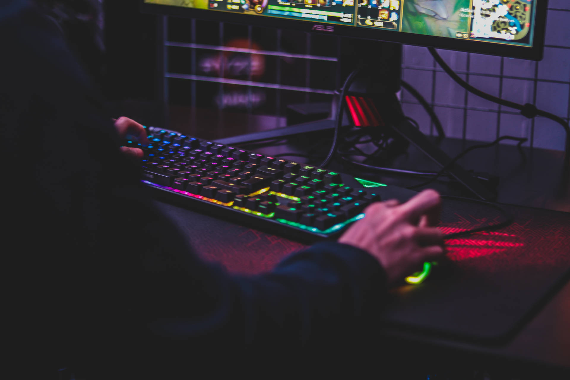 玩家在黑暗的房間中用發光的鍵盤和滑鼠玩遊戲。 — Asus 壁紙