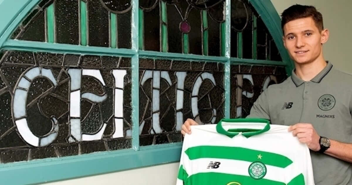  壁紙 — 一名身穿塞爾提克FC Polo衫的年輕男子，在寫有「CELTIC」的彩繪玻璃窗前自豪地舉起一件綠白條紋足球球衣。