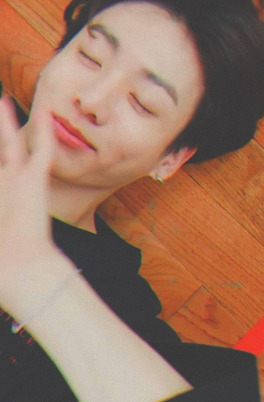 年輕男子在木地板上平靜地睡覺，手靠近臉部。 — Bts 壁紙