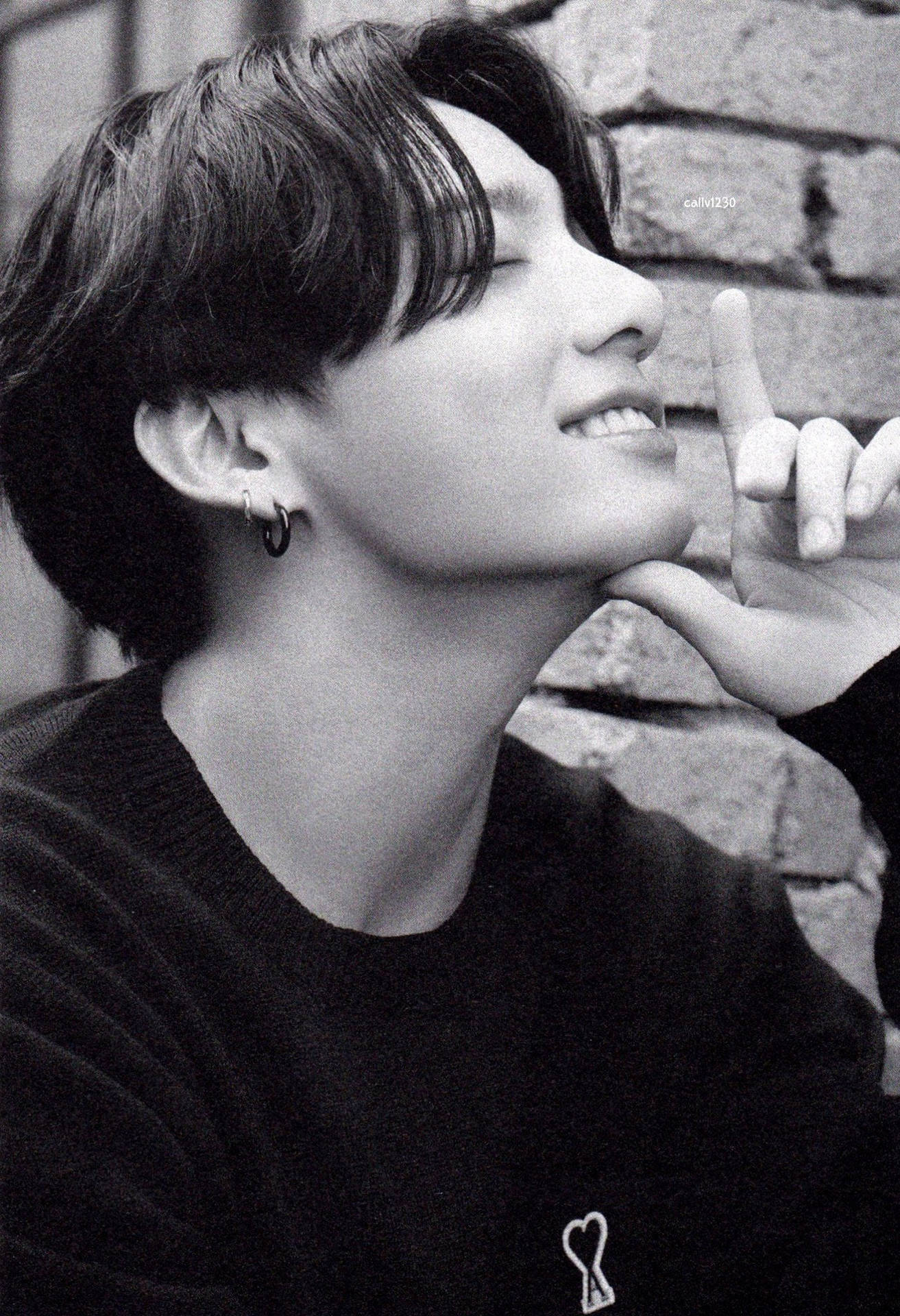 年輕男子微笑，手托下巴靠磚牆，黑白風格 — Jungkook 壁紙