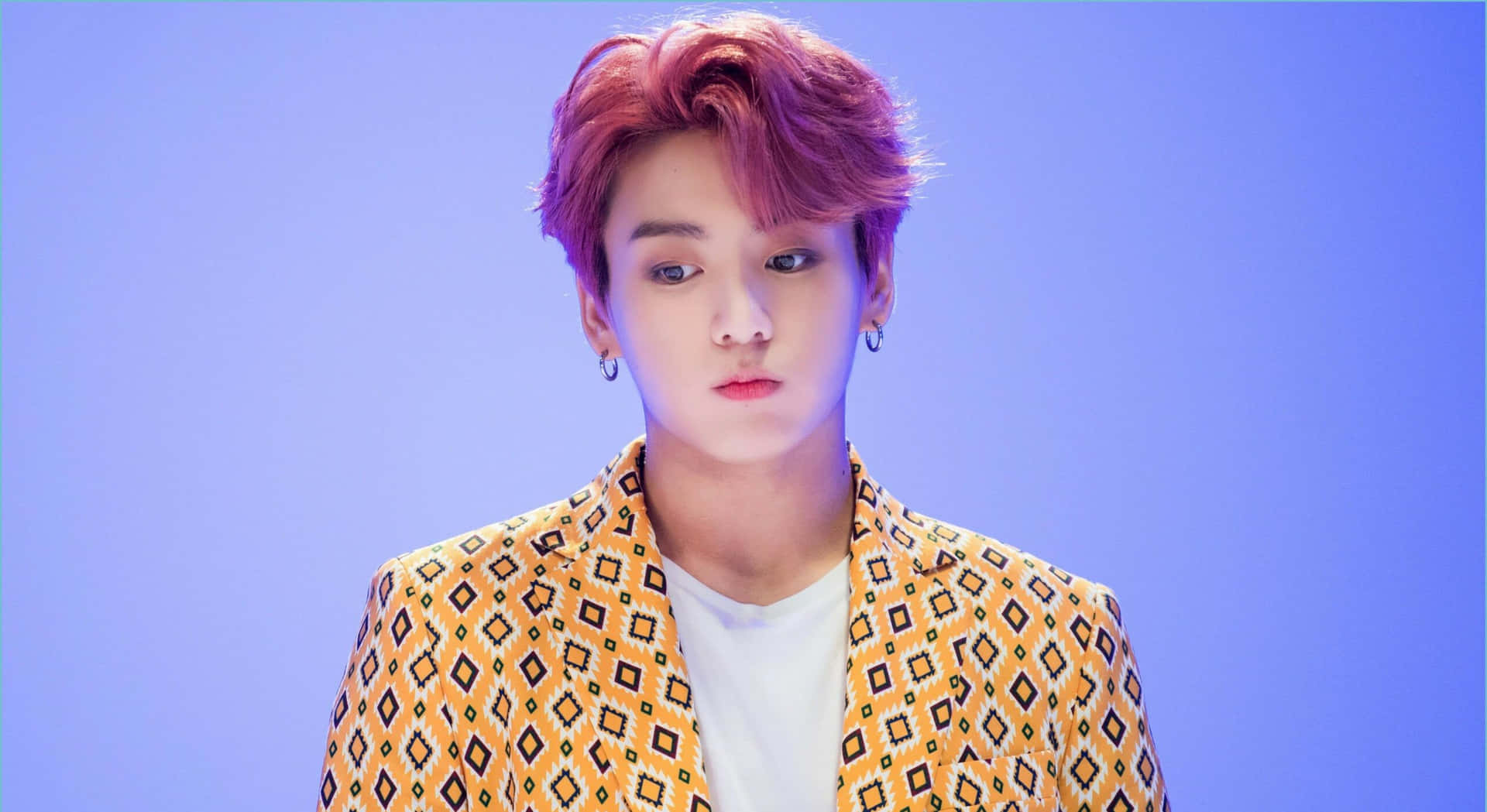 粉紅髮年輕男子穿圖案西裝外套，藍色背景。 — Jungkook 壁紙