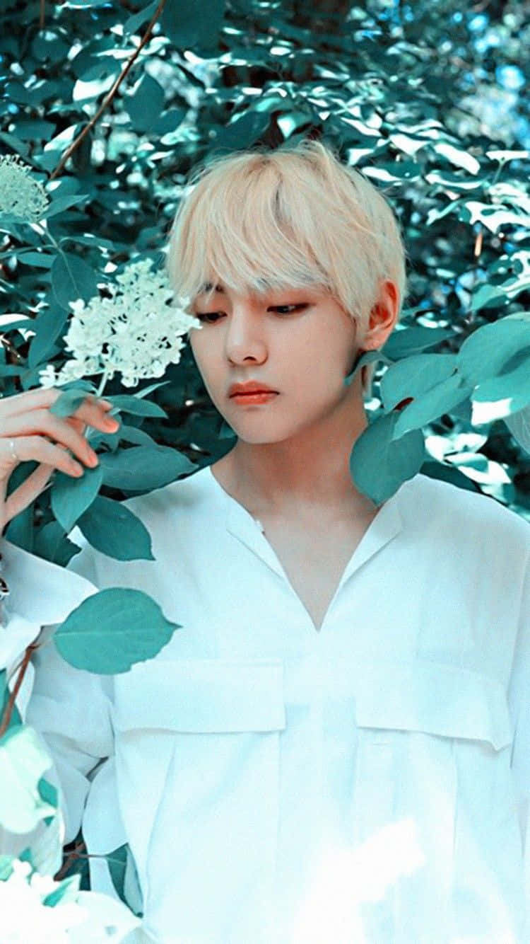 金髮年輕人穿白襯衫，在綠葉和白色花朵中。 — Bts 壁紙