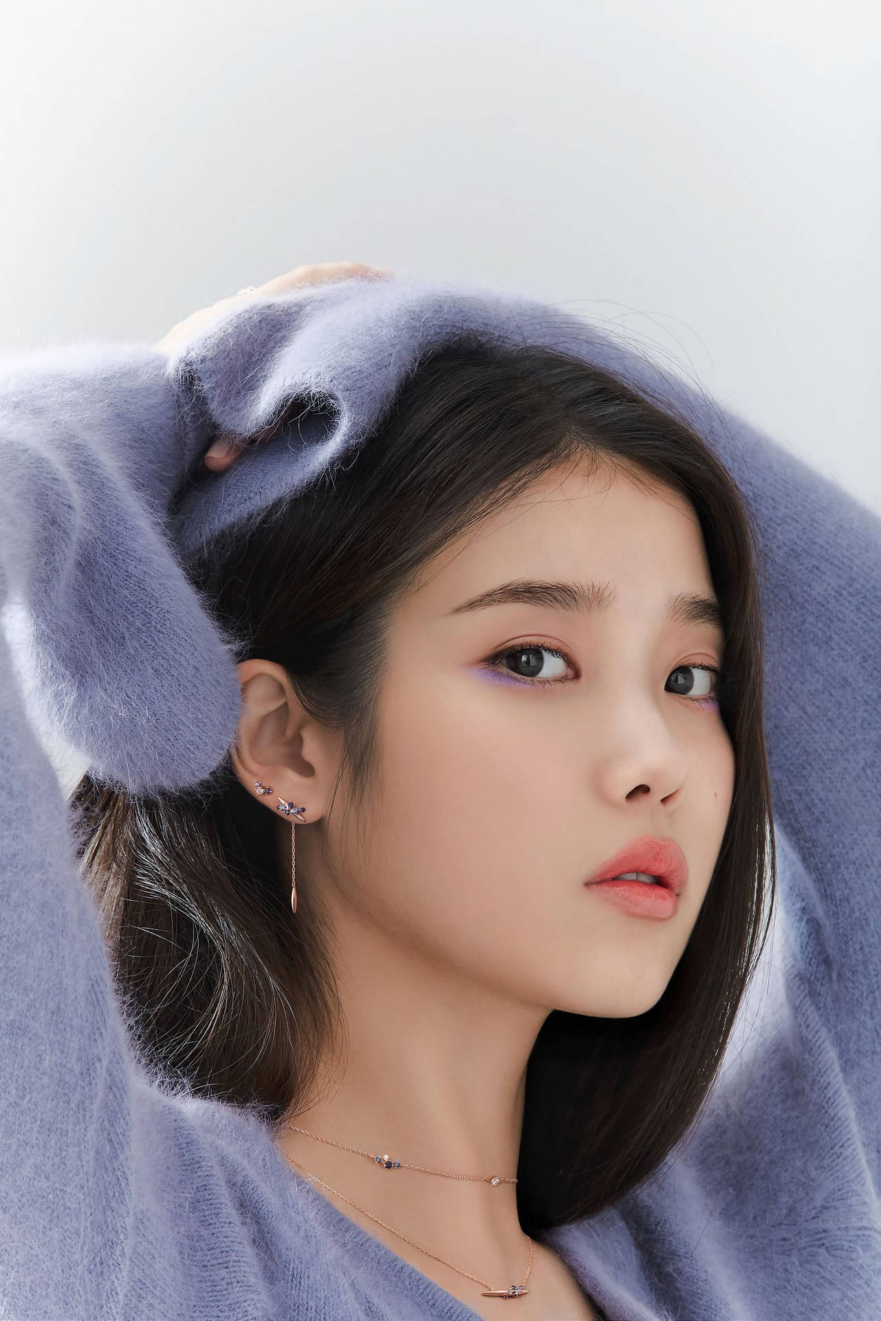 年輕女性穿著薰衣草色毛衣在攝影棚中將毛衣舉過頭頂 — K Pop 壁紙
