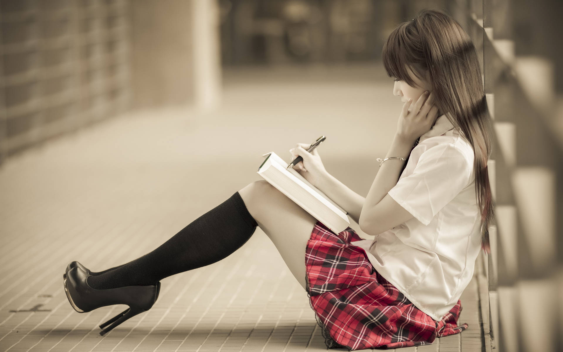一名穿著校服的女孩坐在磁磚地上在筆記本上寫字。 — 中文 壁紙