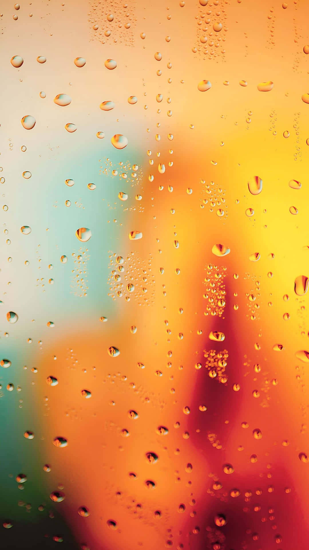  壁紙 — 雨滴依附在窗戶上，顯露出帶有溫暖橙色和冷調青綠色的模糊日落。