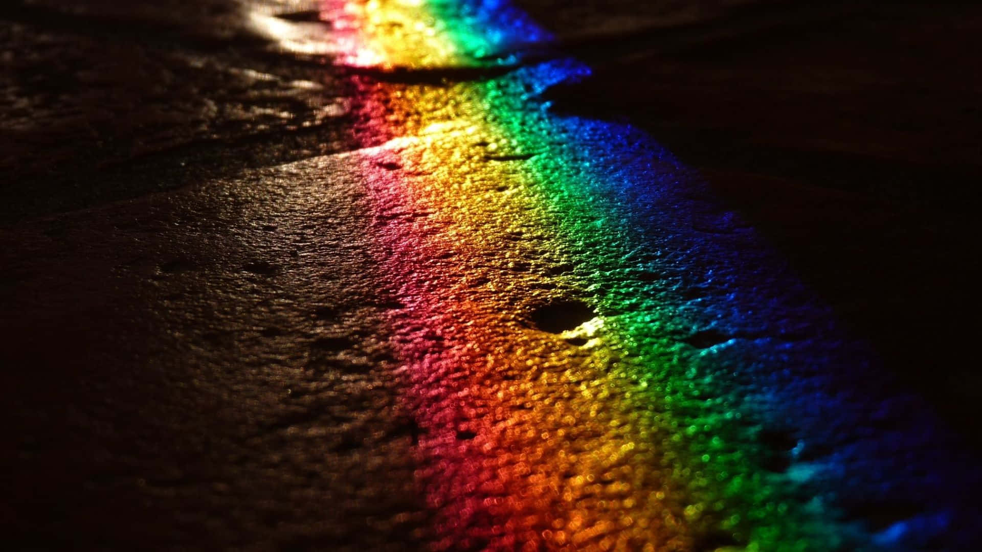  壁紙 — 在黑暗環境中，鮮豔的彩虹光譜反射在潮濕的紋理表面上。