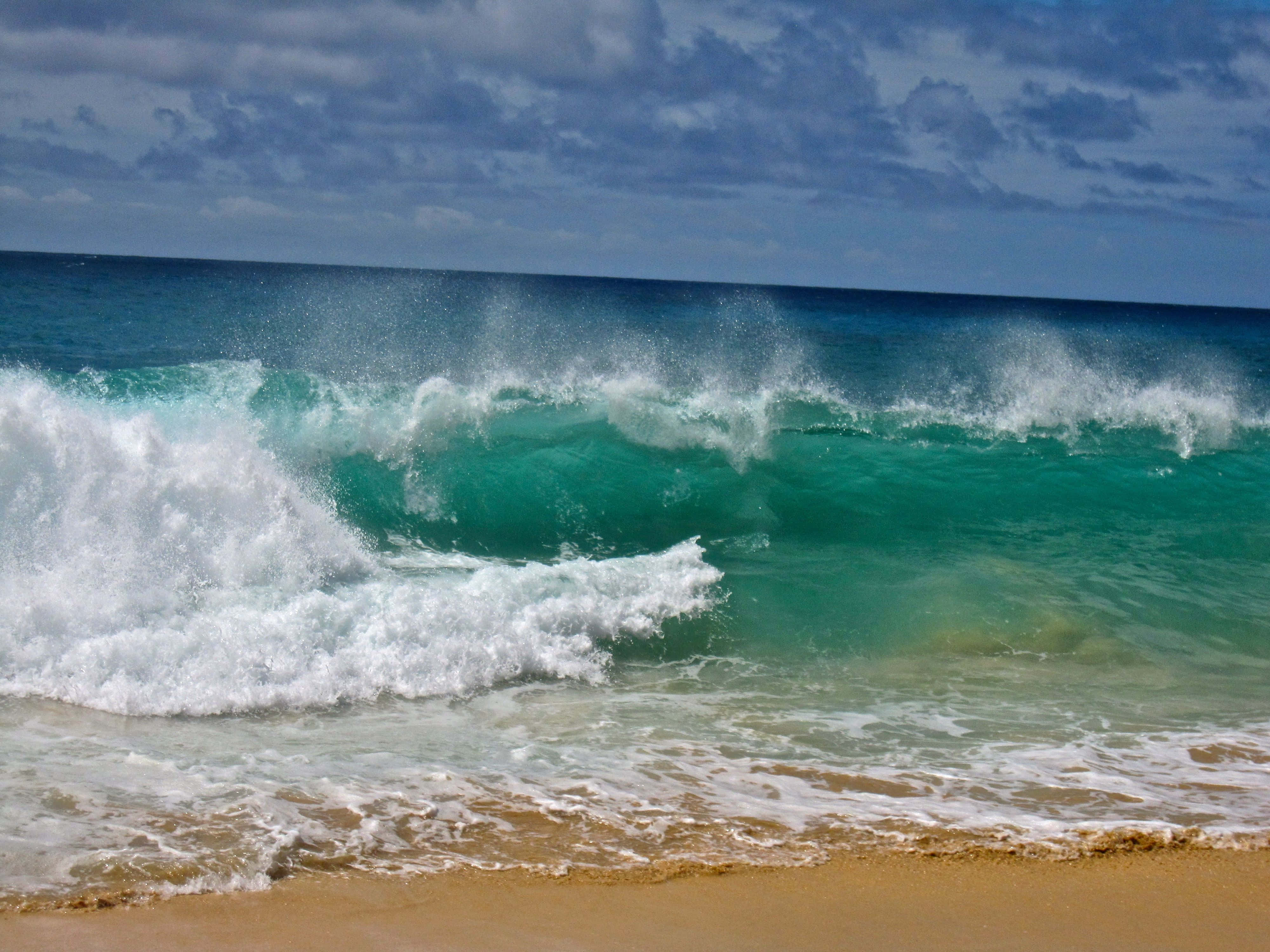 Beach Waves 桌布 壁紙 — 在陰天之下，強勁的藍綠色海浪拍打著金色的沙灘。