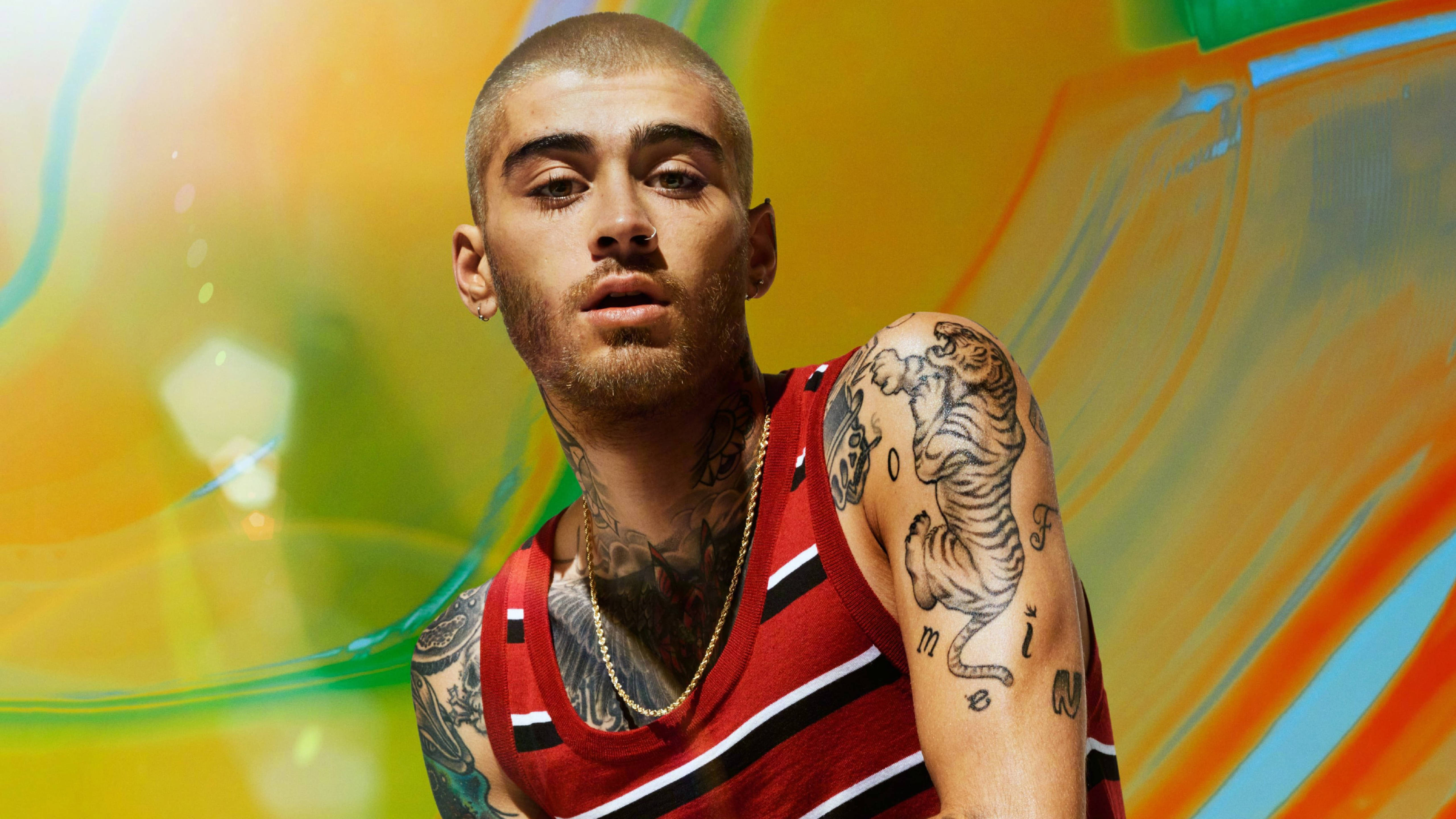 zayn 桌布 壁紙 — Zayn Malik 在充滿活力的抽象背景前，帶有旋轉的橙色、綠色和藍色色調，強烈地凝視著。