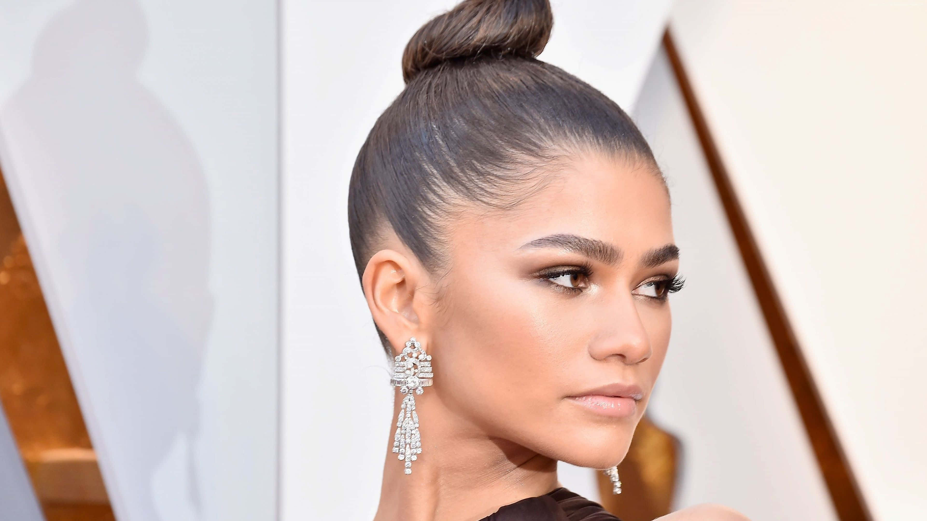 Celebrity 桌布 壁紙 — Zendaya 側面沉思，戴著閃耀的鑽石吊燈耳環和光滑的高髻髮型。