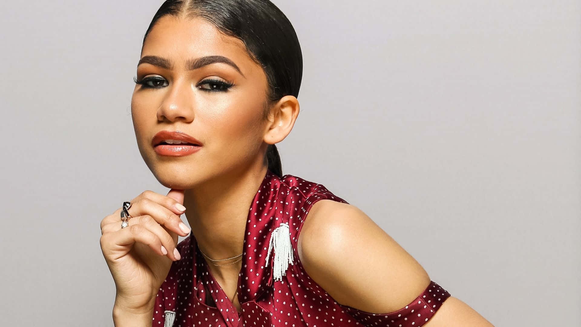 Celebrity 桌布 壁紙 — Zendaya 在純灰色工作室背景前自信地擺姿勢，身穿紅色圓點上衣。