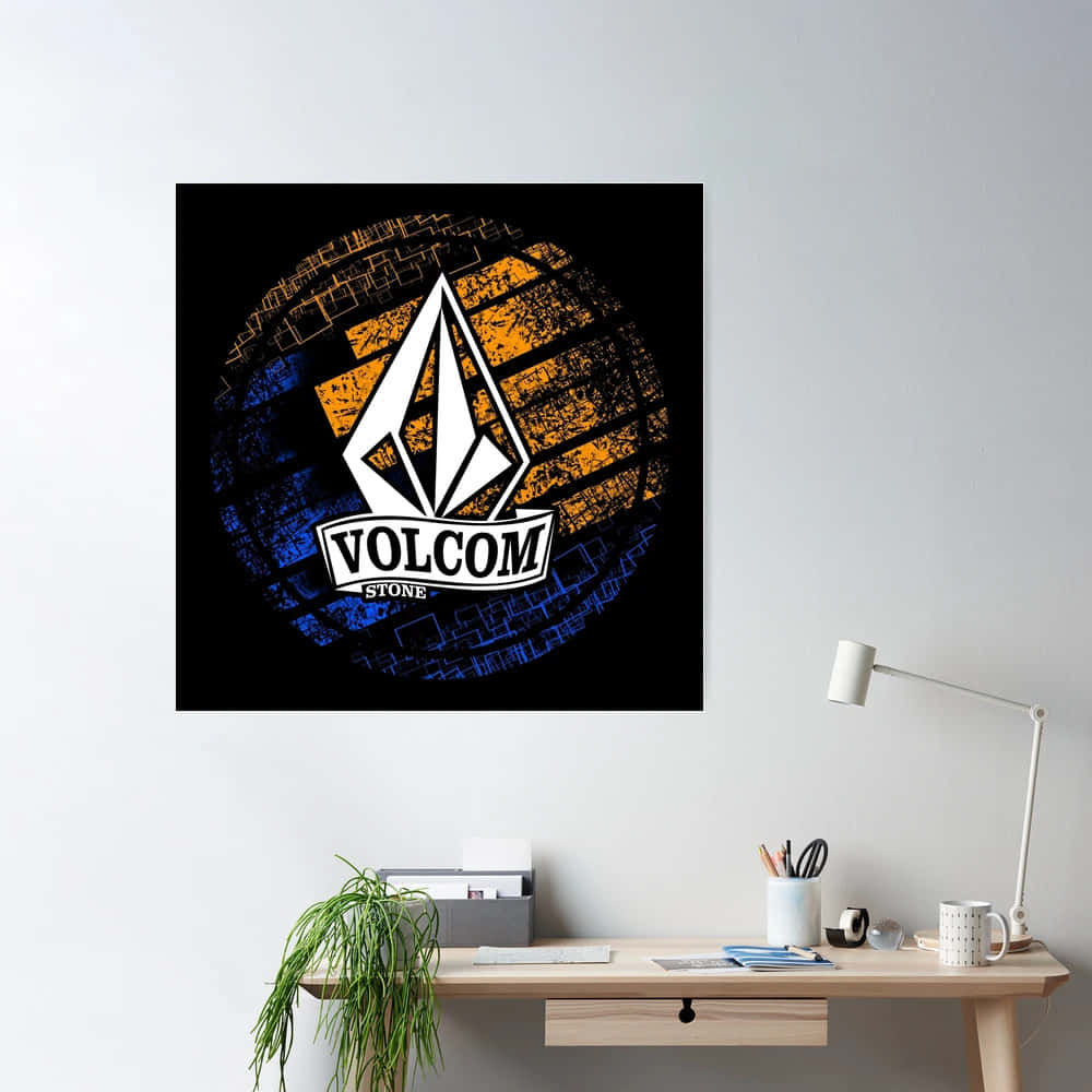  壁紙 — 一張Volcom Stone標誌海報，帶有磨損的橙色和藍色圓形背景，掛在白色牆上，下方是一張簡約的木桌。