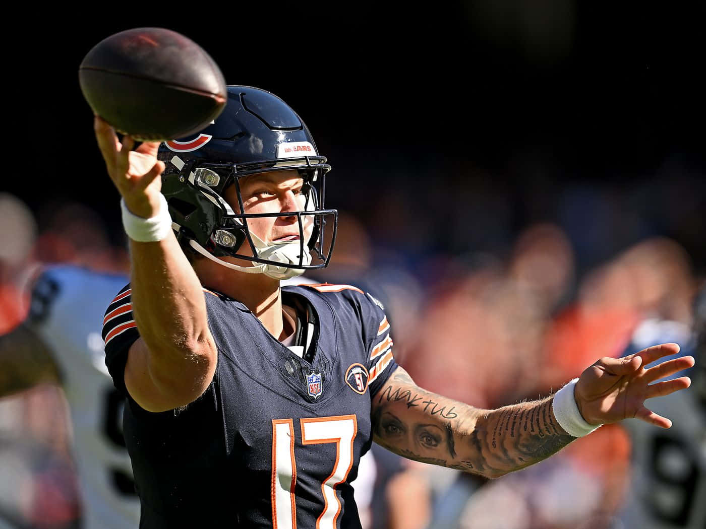  壁紙 — 芝加哥熊隊的四分衛身穿海軍藍球衣，背號17，在明亮的日間比賽中擲出橄欖球。
