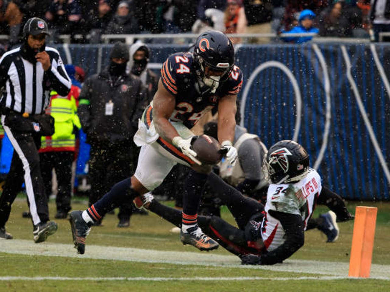  壁紙 — 芝加哥熊隊球員在潮濕的NFL比賽中跳過俯衝的亞特蘭大獵鷹隊防守球員。
