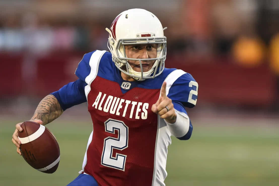  壁紙 — 一名專注的美式足球四分衛，身穿紅藍白三色Alouettes 2號球衣，在比賽中帶球奔跑並向前指。