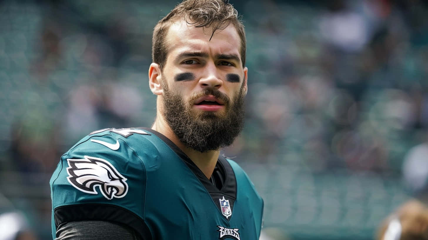  壁紙 — 一名專注的NFL美式足球員，留著鬍鬚並塗上球隊面部彩繪，身穿綠色老鷹隊球衣，凝視前方。