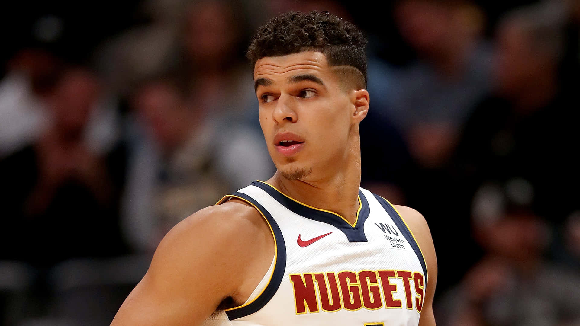 身穿金塊隊球衣的職業籃球運動員在比賽中專注。 — NBA 壁紙