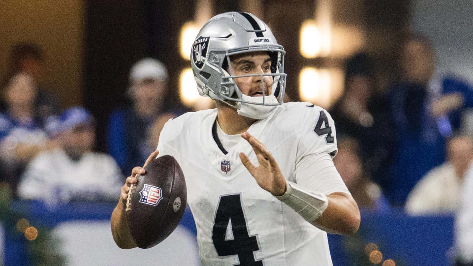  壁紙 — 一位專注的NFL四分衛身穿白色球衣背號四號，在體育場燈光下準備在比賽中傳球。
