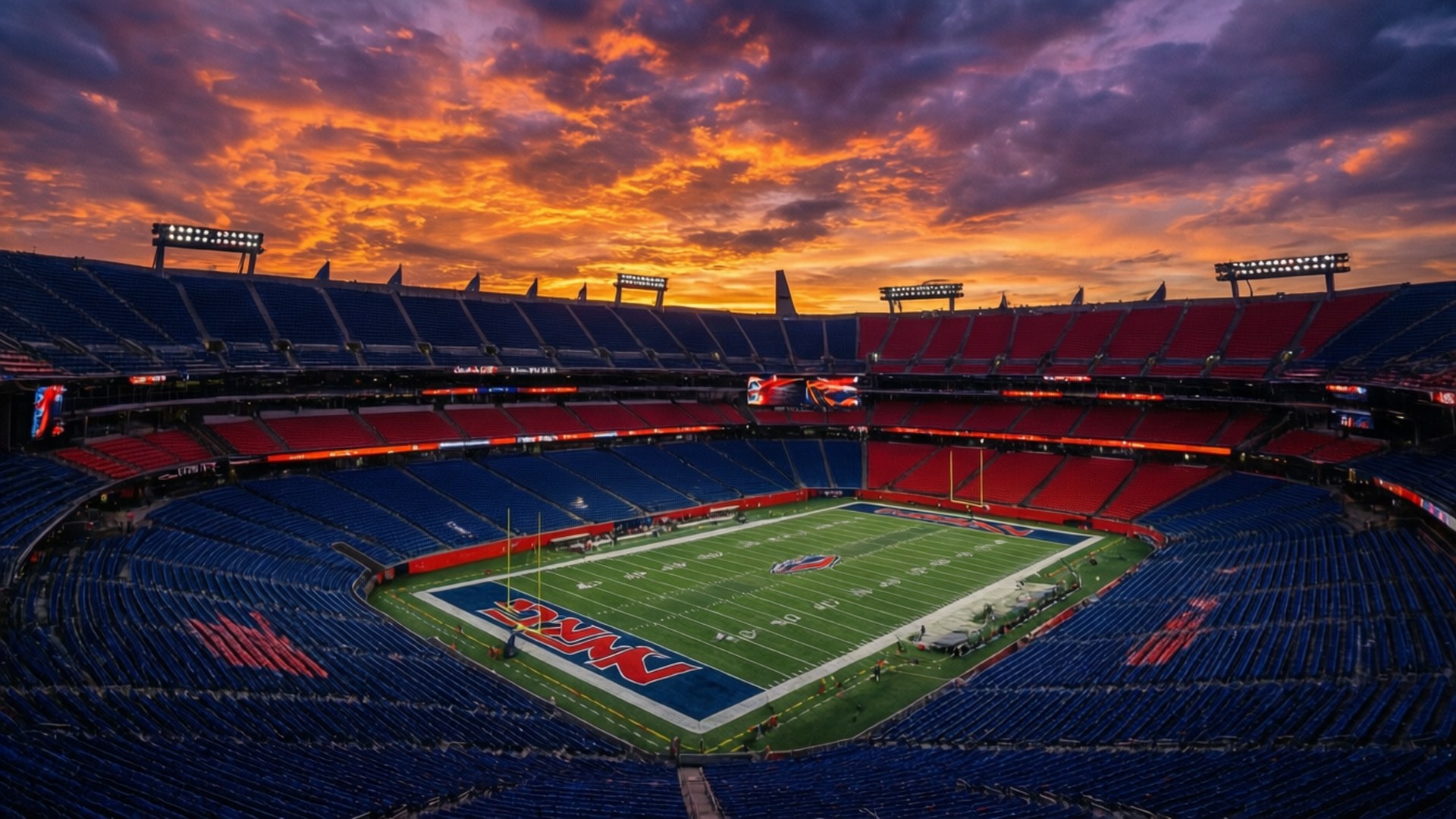 Sunset Over NRG Stadium 壁紙 — 足球場的鳥瞰圖，日落時分，火紅色的橙雲籠罩著空蕩蕩的藍色和紅色座位。