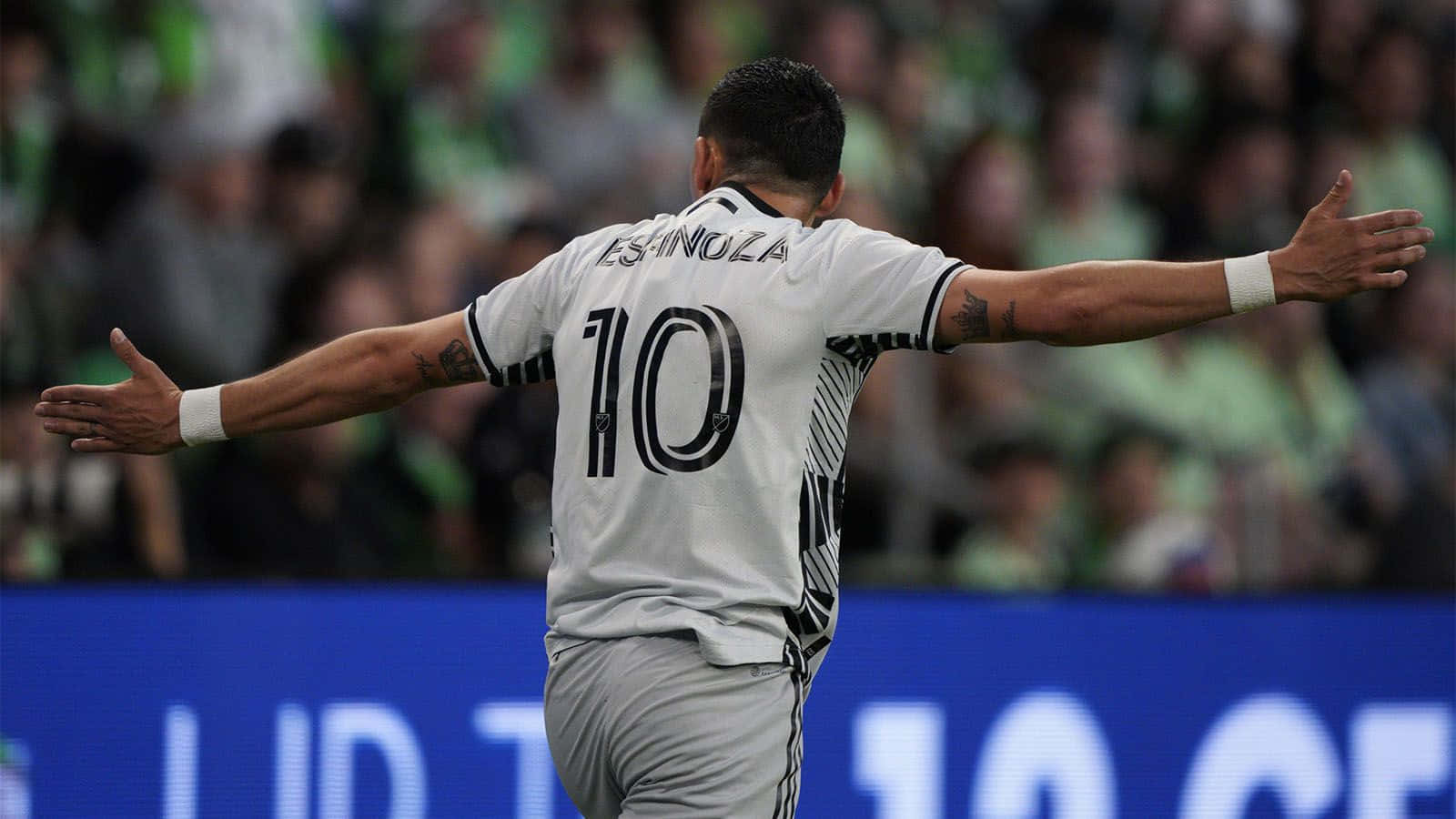  壁紙 — 足球員查維亞·埃爾南德斯（Chicharito）在球場人群中張開雙臂慶祝，身穿10號球衣。